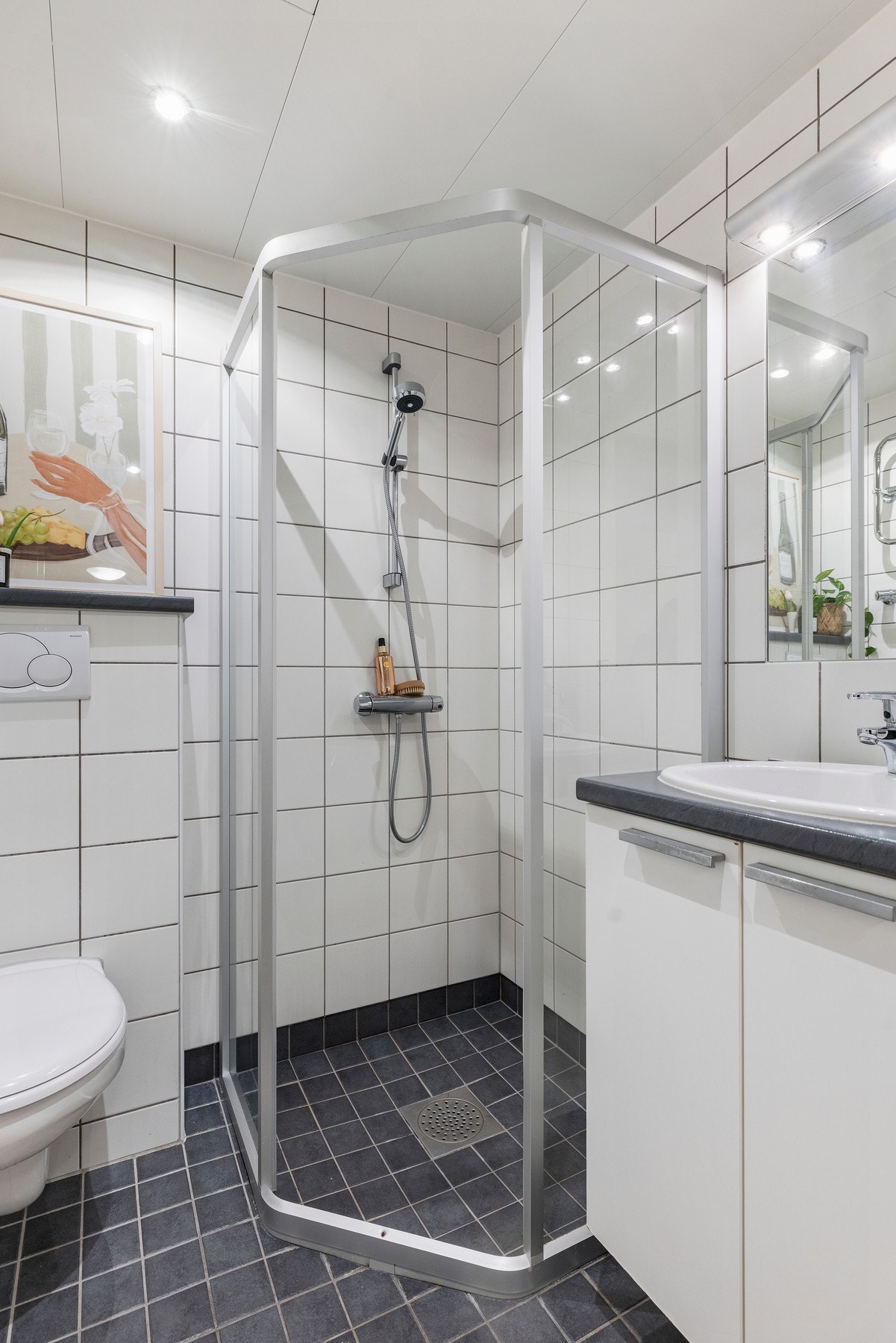 Dusjhjørne med termostatstyrt dusjbatteri i krom og hånddusj. Veggmontert servantinnredning med benkeplate og nedfelt vask med ett-greps armatur i krom Galleribilde