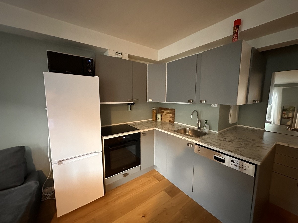 Åpen kjøkkenløsning med stekeovn, koketopp, kjøleskap og fryser, mikrobølgeovn og oppvaskmaskin Galleribilde