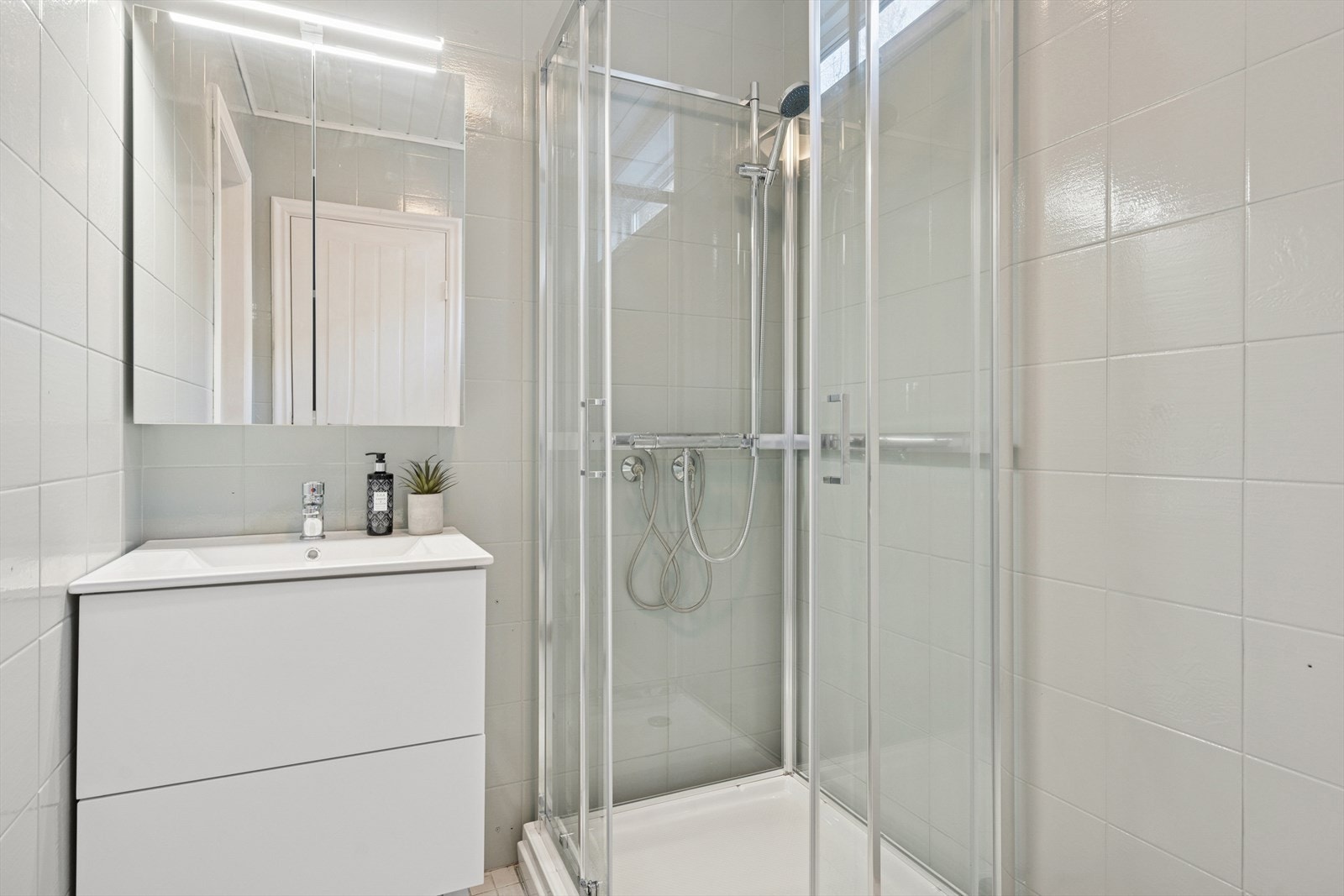 Bad i første etasje med dusjkabinett, servant m/speil og toalett samt inngang til badstue, flisene på veggen her er malt med epoxy Galleribilde