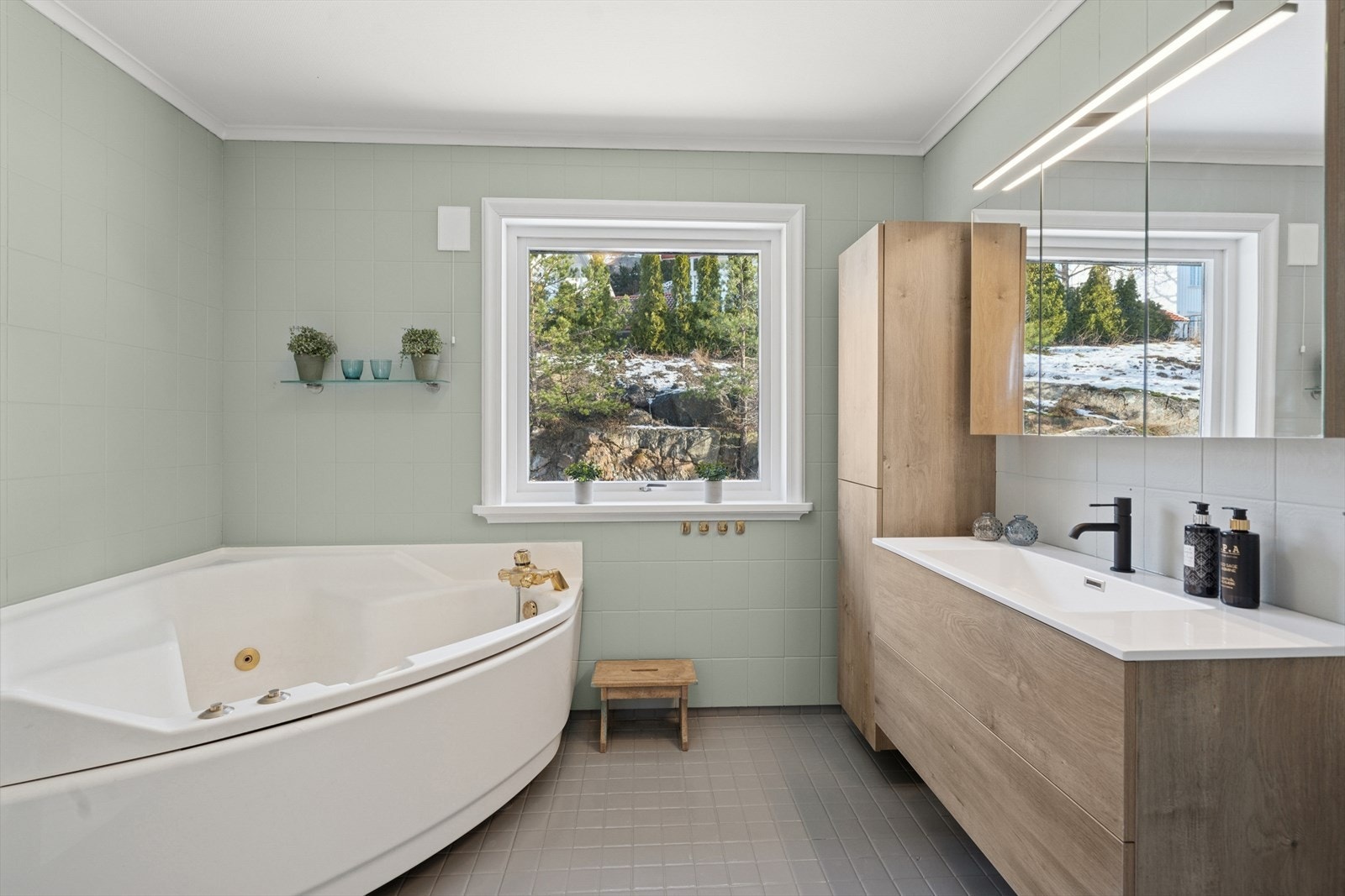 Badet i hovedetasjen med nyere servant og skap. Badekar og toalett. På gulvet er flisene malt med epoxy og på veggene er det malte baderomsplater Galleribilde