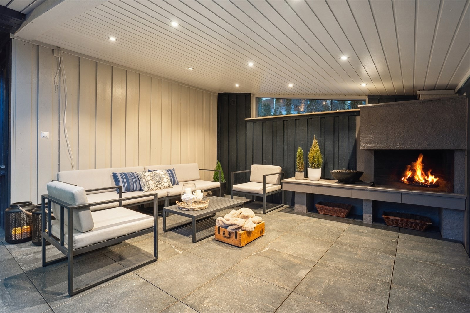 Delikat uteområde med peis. Det er lagt fliser på gulvet og overbygget gjør at du kan nyte sene kvelder Galleribilde