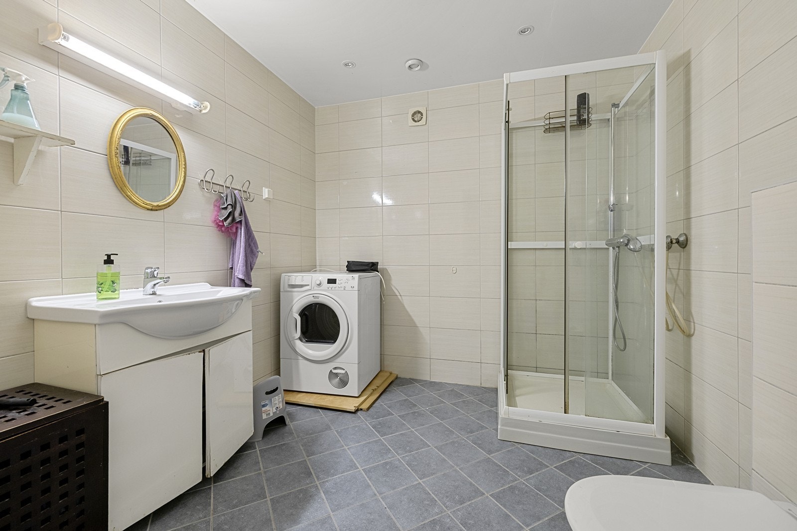 Flislagt bad i kjeller med dusjhjørne, servant og opplegg for vaskemaskin. Galleribilde