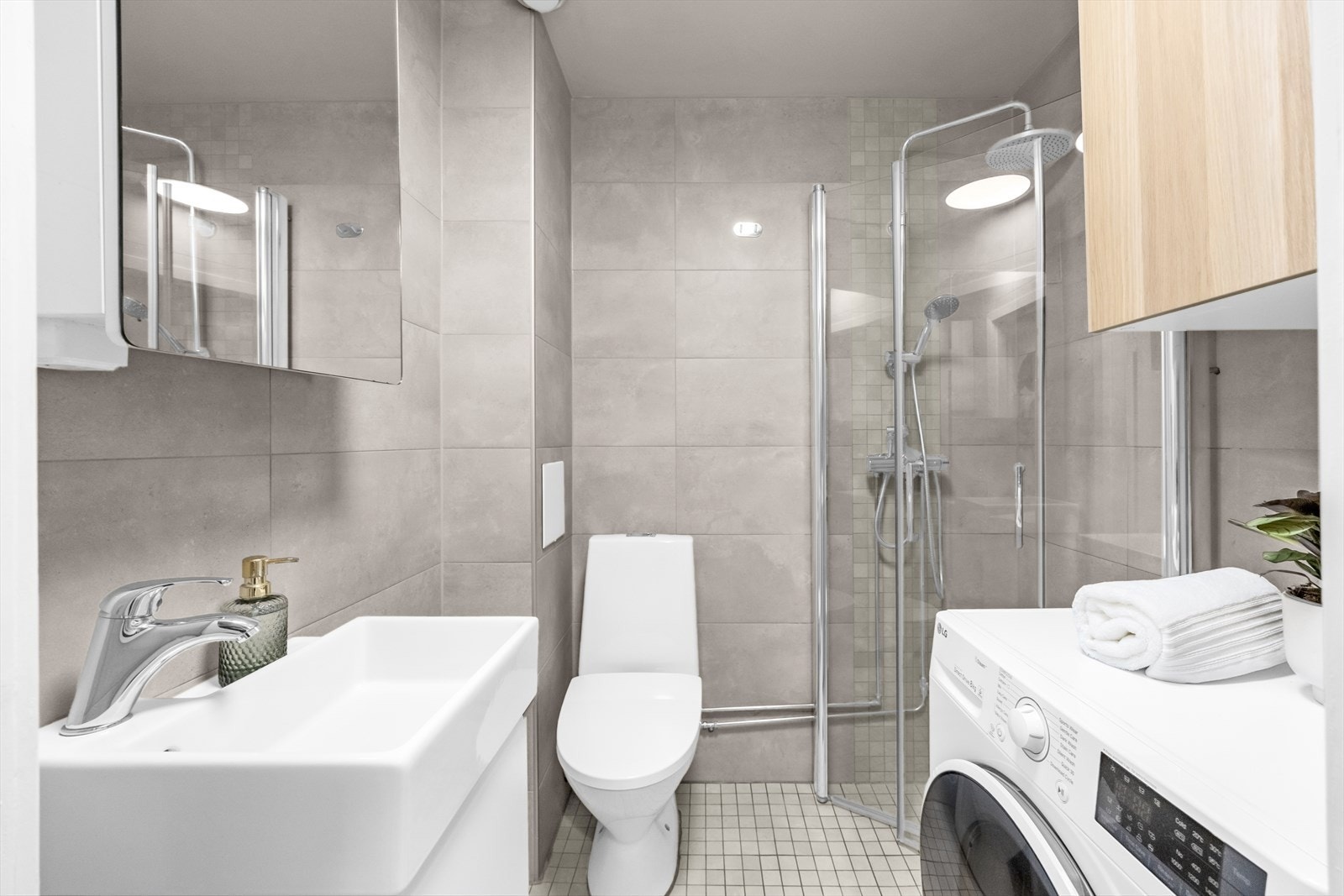 Pent flislagt bad fra 2016 innredet med servantskap med ett-greps blandebatteri, speilskap, veggskap, gulvstående toalett, avskjermet dusjhjørne med glass, blandebatteri og dusjgarnityr. Galleribilde