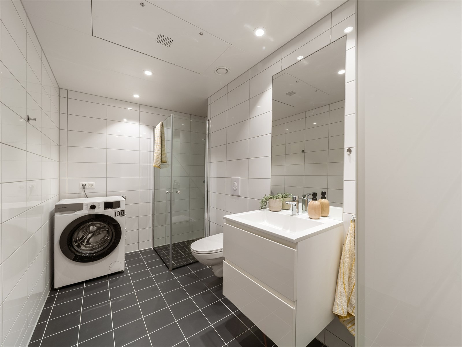 Pent, helfliset baderom med opplegg for vaskemaskin og tørketrommel. Galleribilde