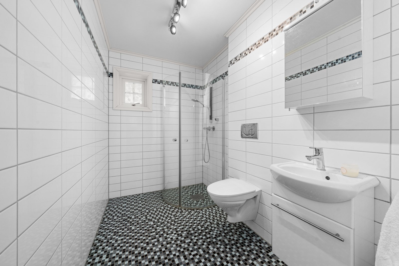 Baderom nummer to har dusjløsning, vegghengt toalett og servant på skapseksjon. Galleribilde