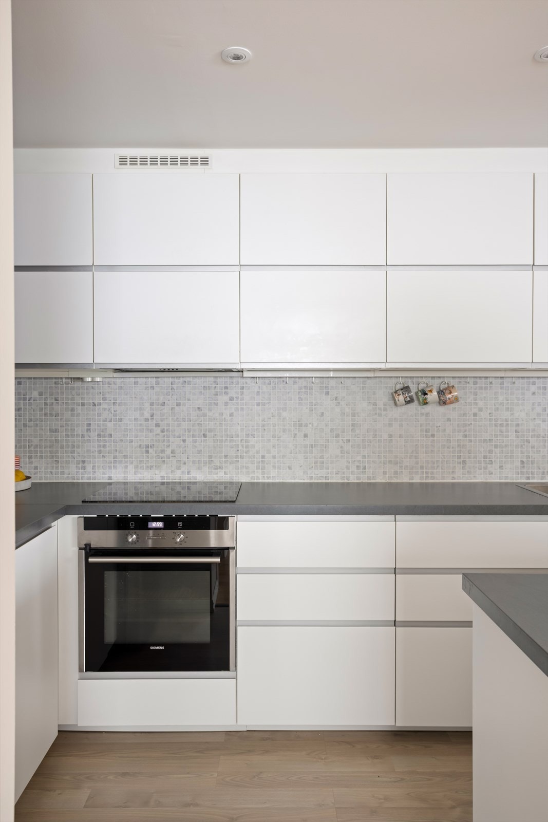 Kjøkkenet har en moderne innredning med glatte, hvite fronter og helhetlige løsninger. Galleribilde