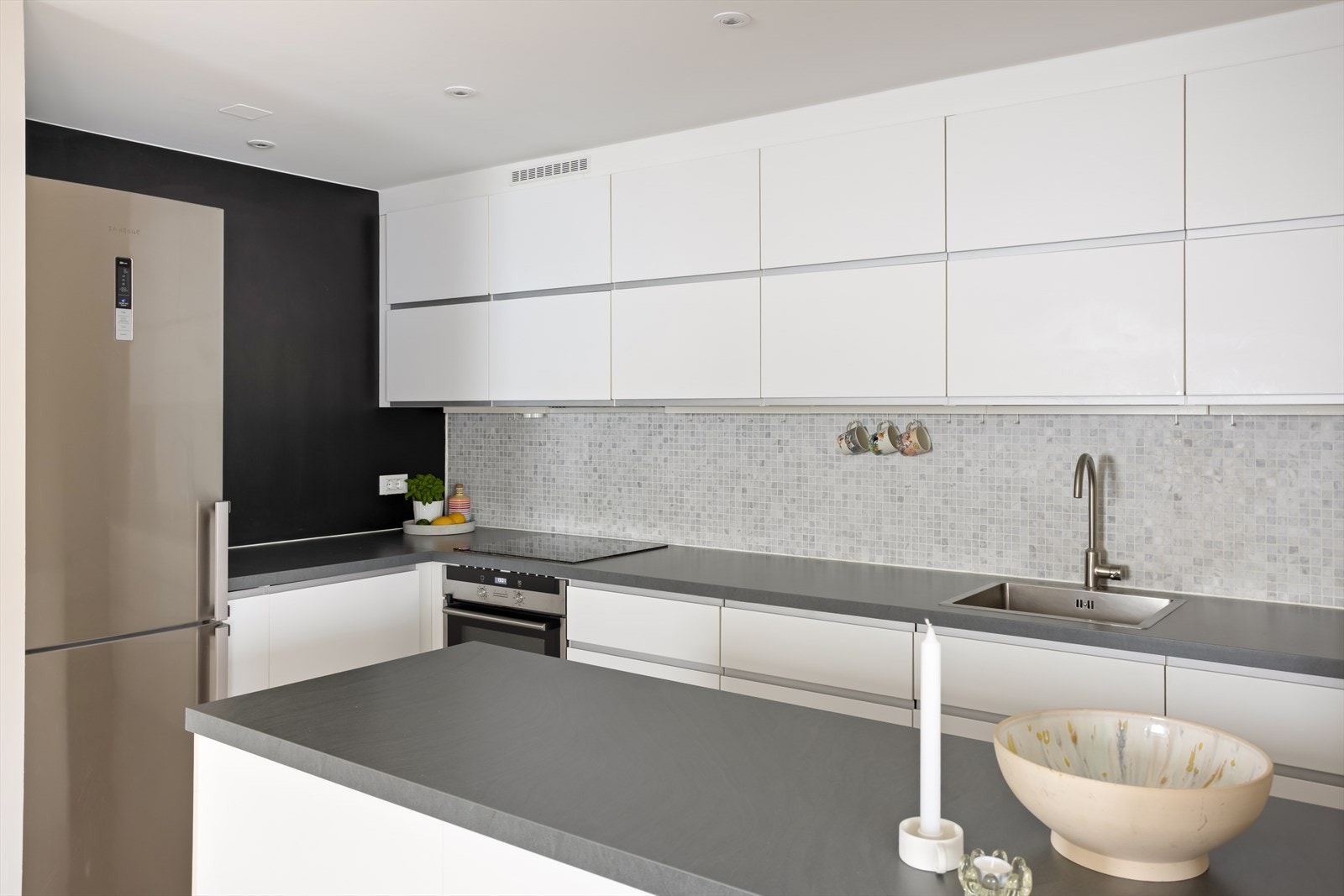 Rikelig med skap- og benkeplass gir funksjonelle arbeidsforhold, samtidig som kjøkkenøya bidrar både med ekstra arbeidsflate og blir et naturlig skille mot stuen. Galleribilde