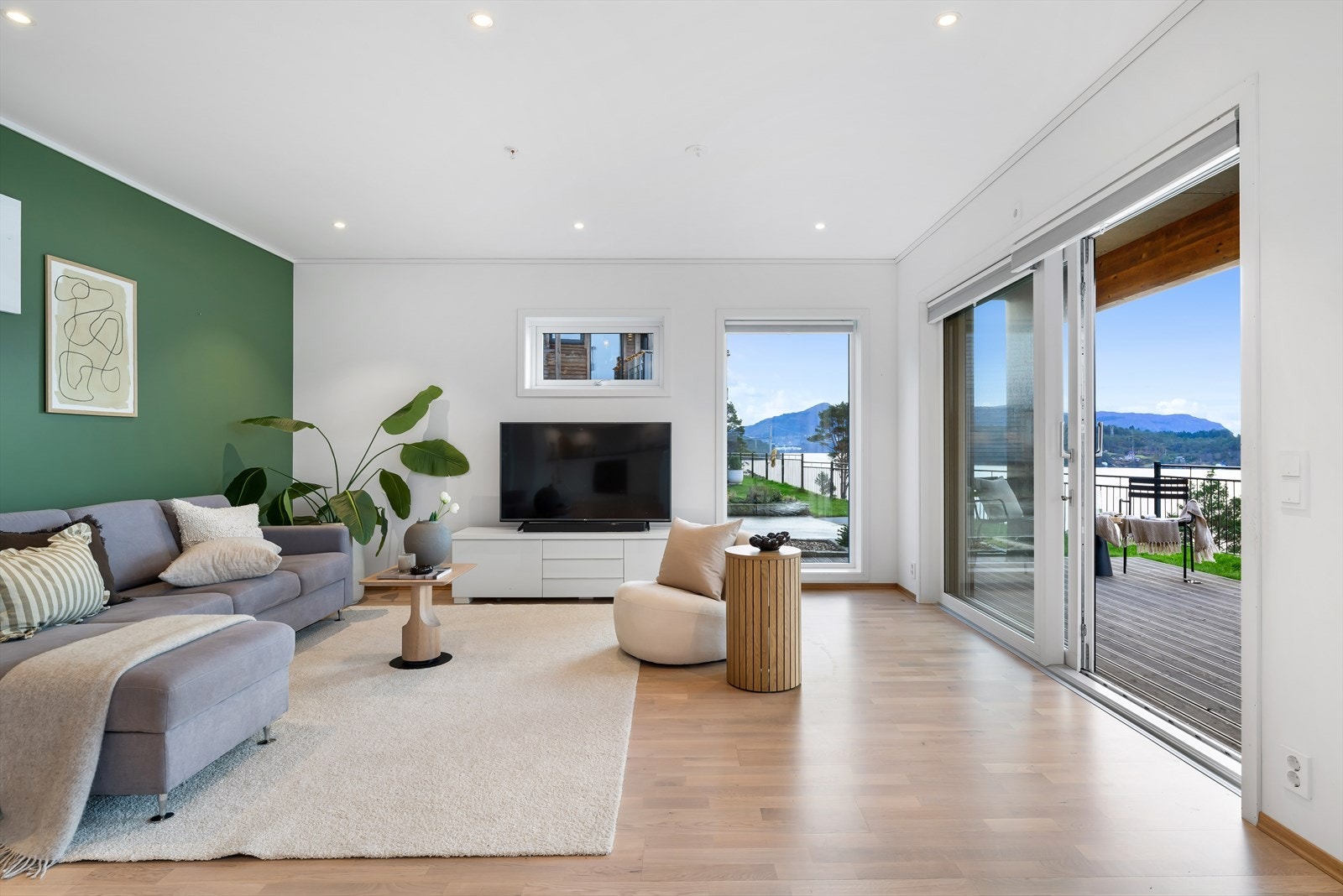 Lys og moderne stue med store vinduer og naturskjønn utsikt. Utgang til romslig terrasse for avslapning og hygge. Galleribilde