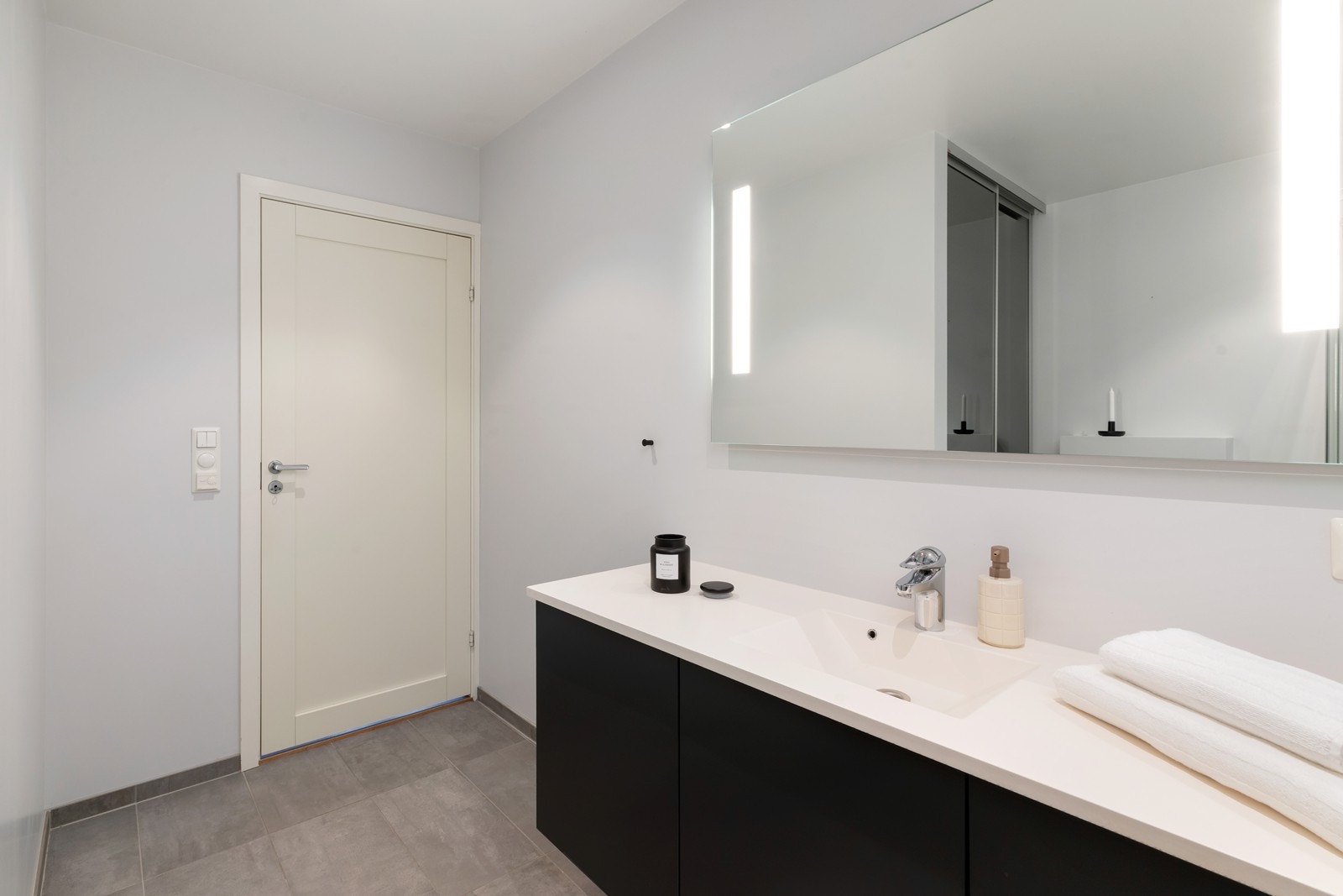 Baderommet er delvis fliselagt med vegghengt toalett, dusjhjørne og servant med oppbevaring. Galleribilde