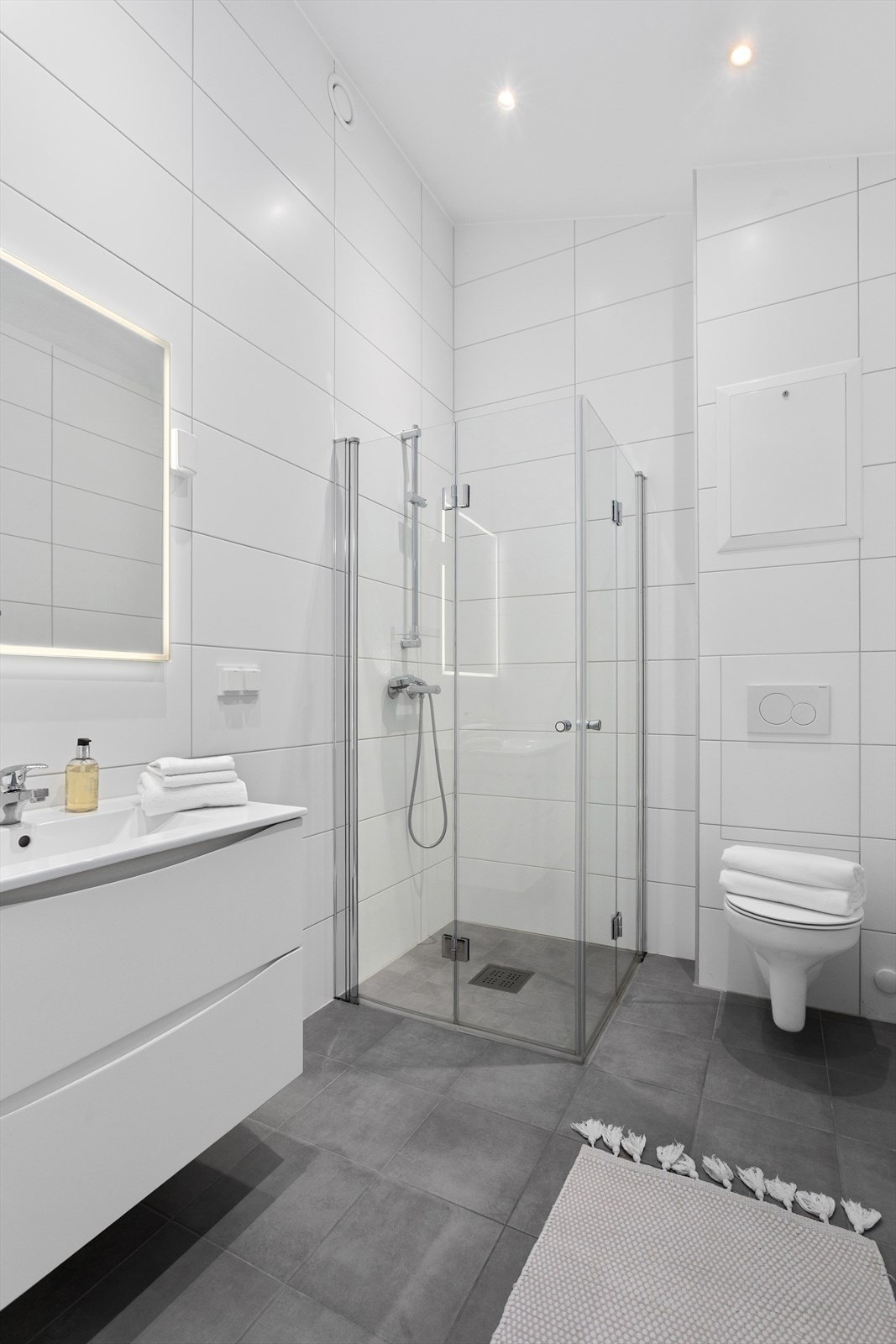 Badet er holdt i nøytrale og fine farger med downlights i tak og varmekabler i gulv Galleribilde