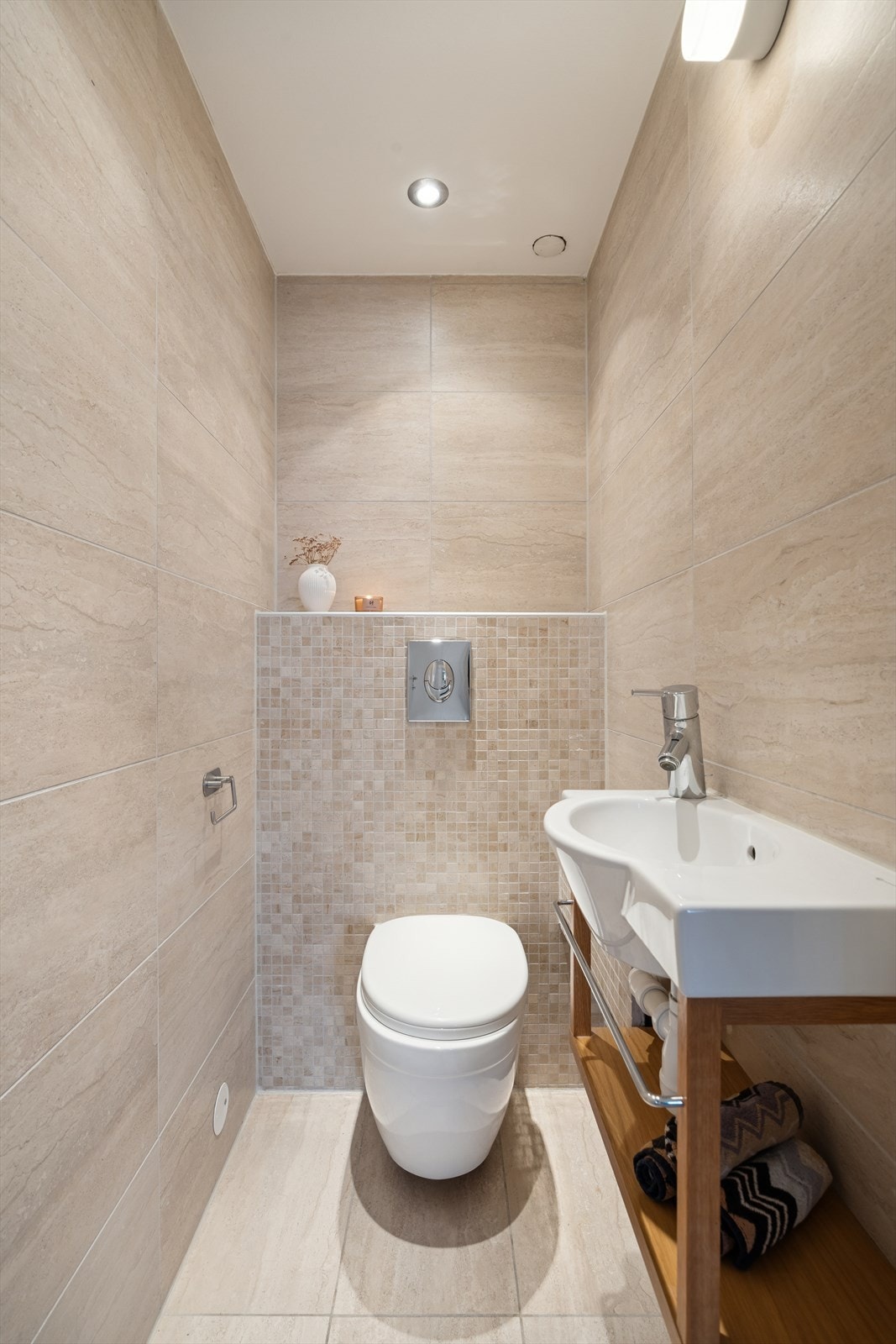 Vegg i vegg med badet finner du et moderne flislagt toalettrom (fra 2016) med vegghengt toalett og servantinnredning Galleribilde