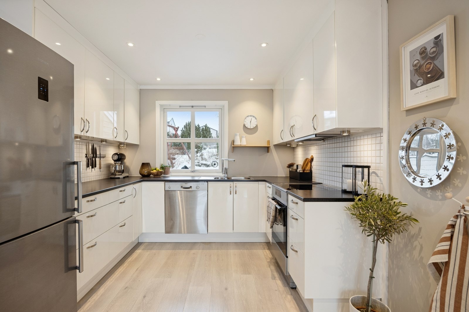 Innredningen er stilren med hvite glatte fronter, laminert benkeplate og fliser på vegg over benk (innredning fra ca. 2009) Galleribilde