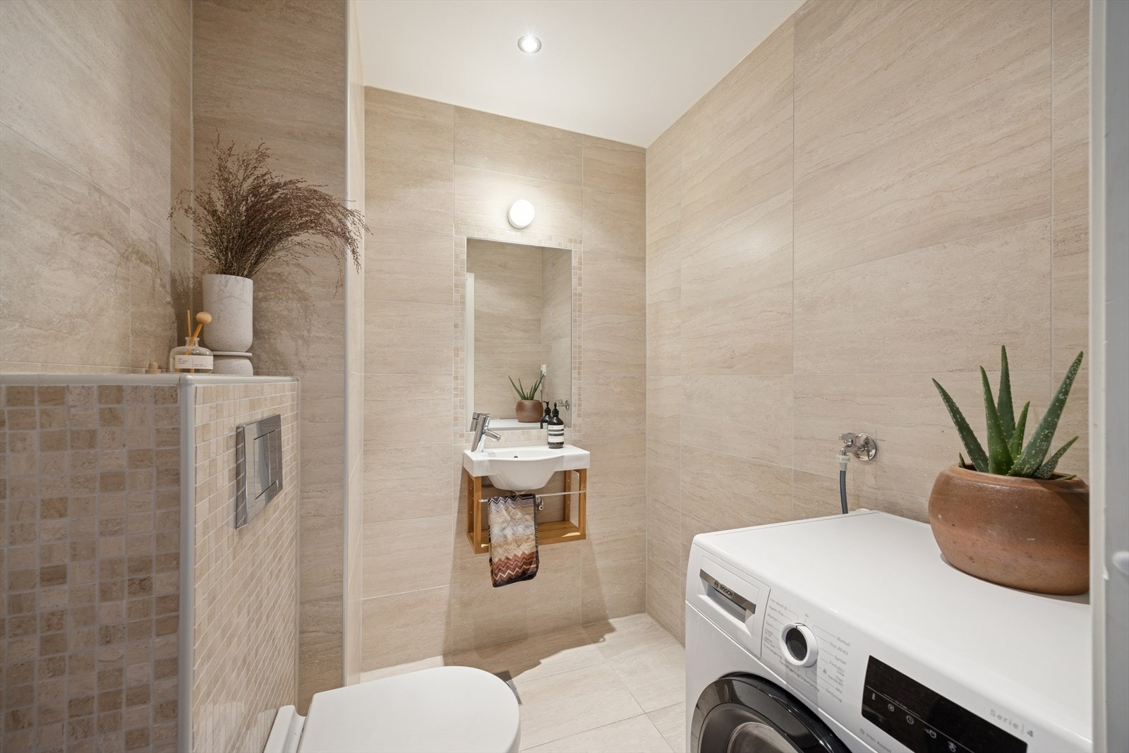 Toalettrommet (opprinnelig bod - ikke omsøkt) er flislagt og har gulvvarme (fra 2016) - Her finner du vegghengt toalett, servant på vegg og opplegg for vaskemaskin Galleribilde