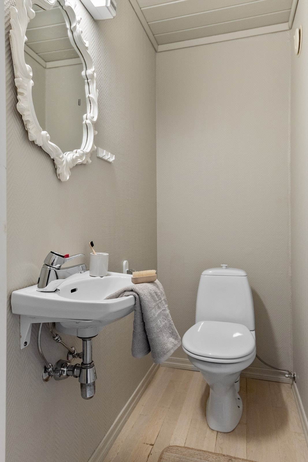 Enkelt toalettrom med toalett og servant med tilkomst fra entréen. Vegg i vegg finner du vaskerom. Galleribilde