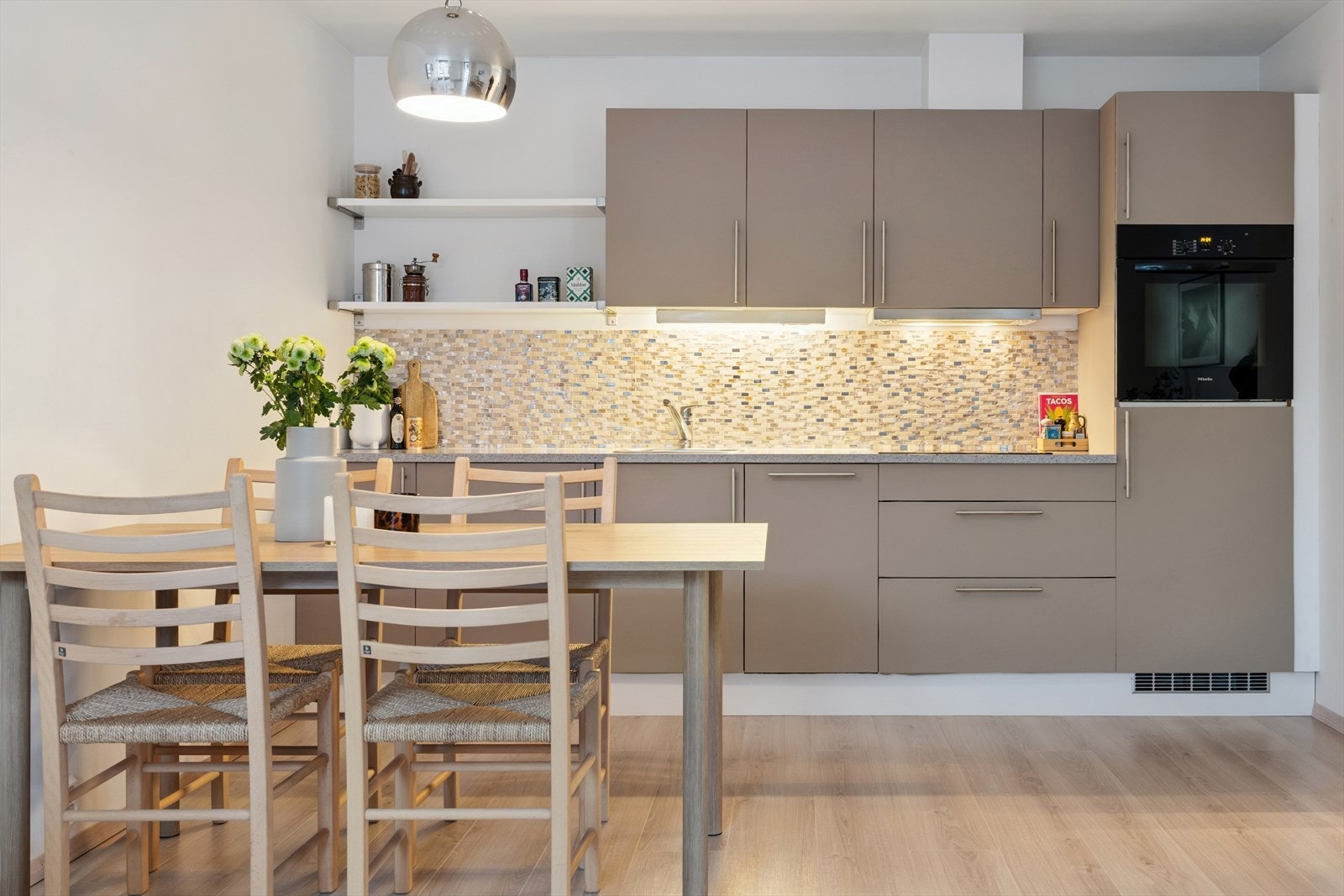 Kjøkkenet har integrerte hvitevarer som kjøleskap, oppvaskmaskin, platetopp og stekeovn. Galleribilde