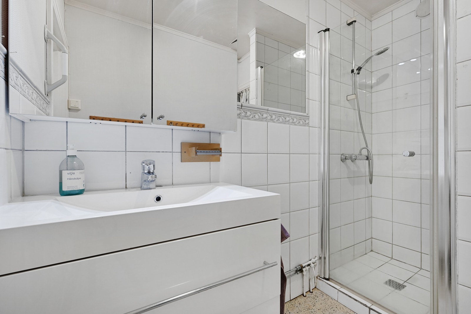 Gulvet er av terrazzo betong, og badet inneholder dusj, klosett og servant i innredning Galleribilde