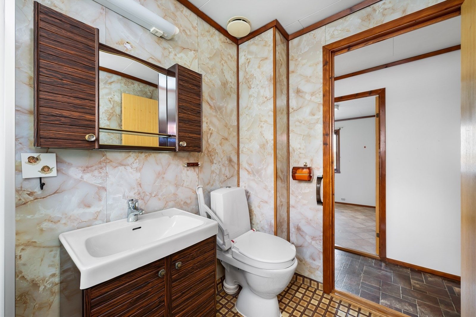 Baderomsinnredningen med overskap er i mørk utførelse. Servanten er heldekkende og toalettet frittstående. Galleribilde