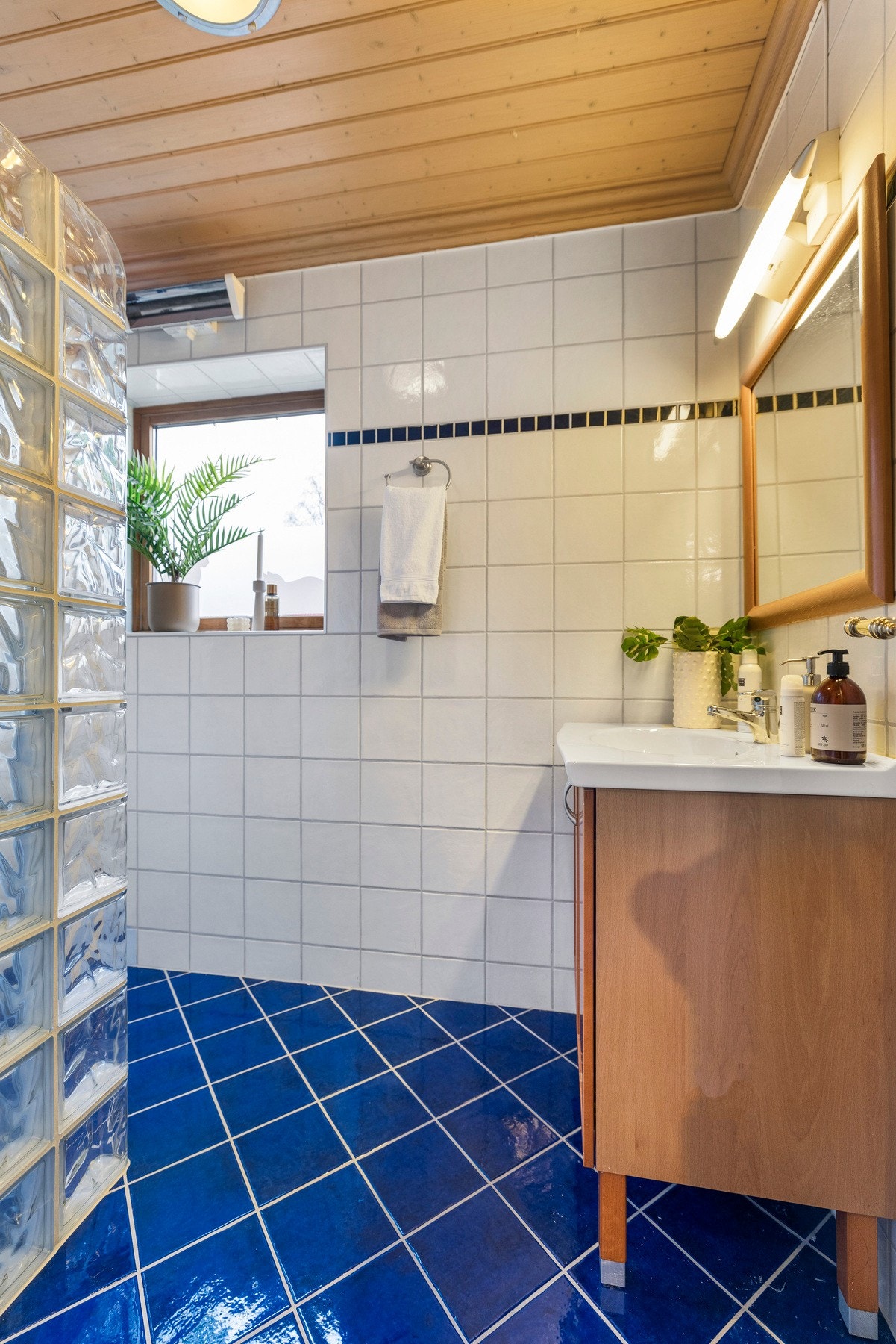 Badet har keramiske fliser på gulv og vegger, samt trepanel i himlingen Galleribilde