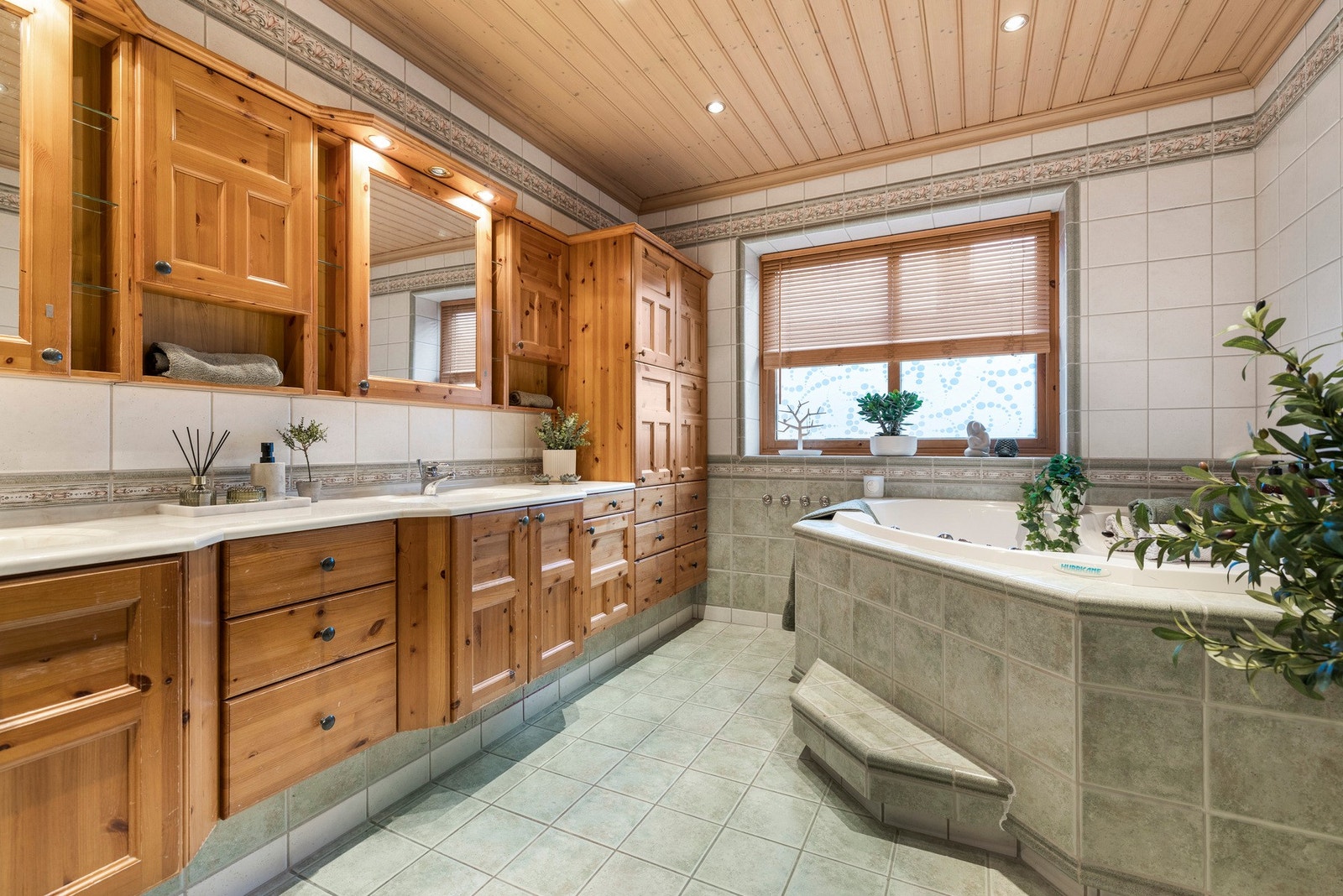 Badet er utstyrt med dobbel servant med skap og speil og et frittstående badekar med flislagt innramming Galleribilde