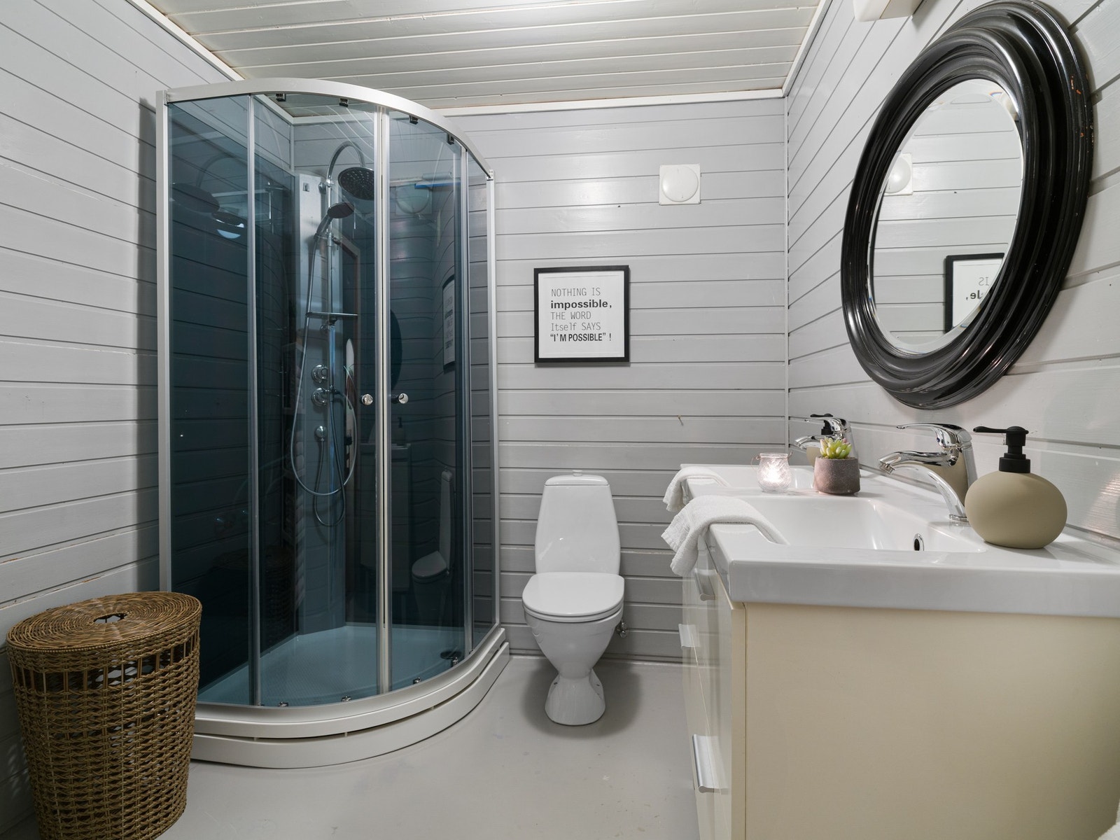 Badet i underetasjen har belegg på gulv med gulvvarme og trepanel på vegger. Rommet har funksjonell innredning med dobbel servantskap, toalett og dusjkabinett. Galleribilde