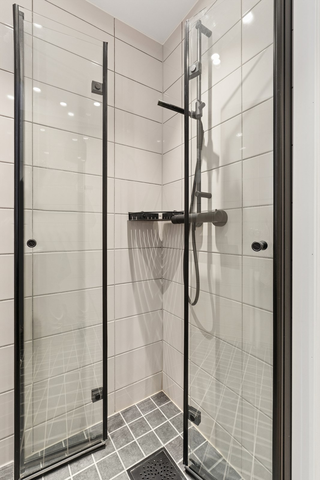 Badet er utstyrt med dusjhjørne med sorte, innsvingbare glassdører og sort dusjarmatur. Galleribilde