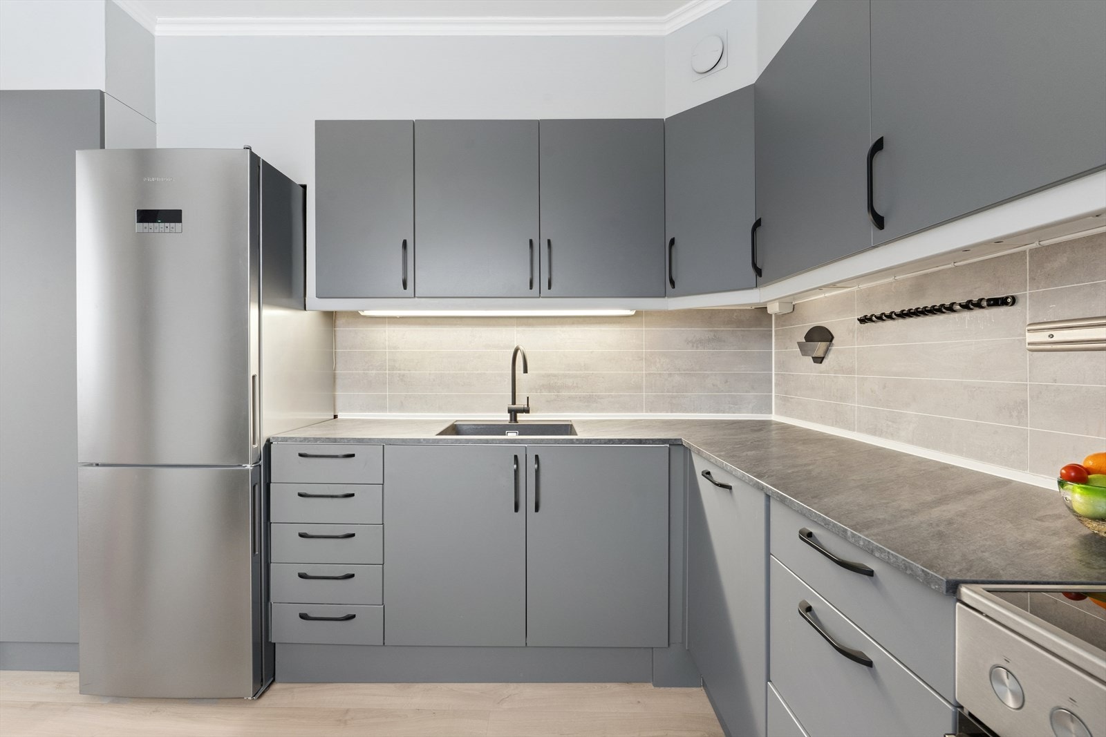 Innredning fra med slette fabrikklakkerte fronter og laminat benkeplate med underlimt oppvaskkum. Galleribilde