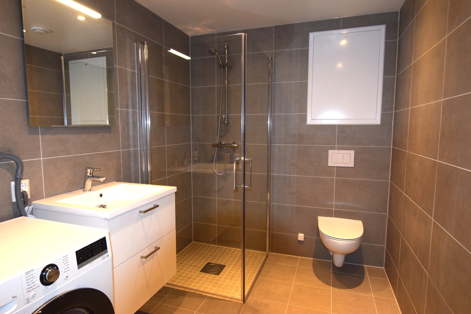 Bad med dusjhjørne og vaskemaskin. Galleribilde