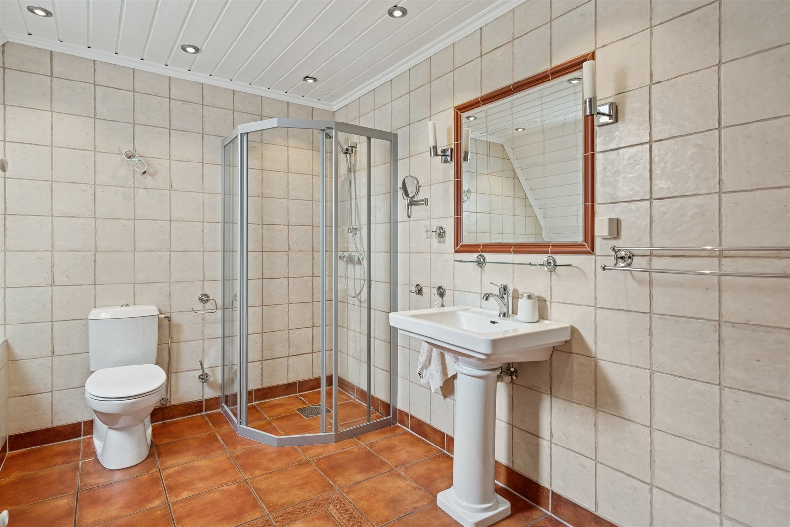 Gulvstående wc og enkel servantinnredning. Det er varmekabler i gulv. Galleribilde