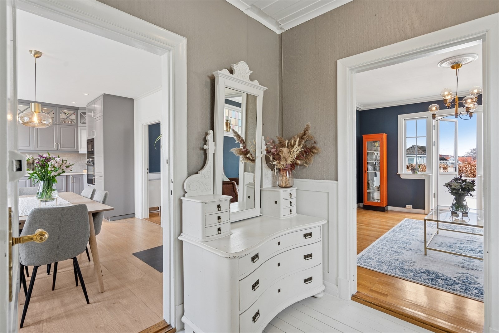 En lys gang som forbinder stue og kjøkken, fylt med naturlig lys og en innbydende atmosfære. Galleribilde