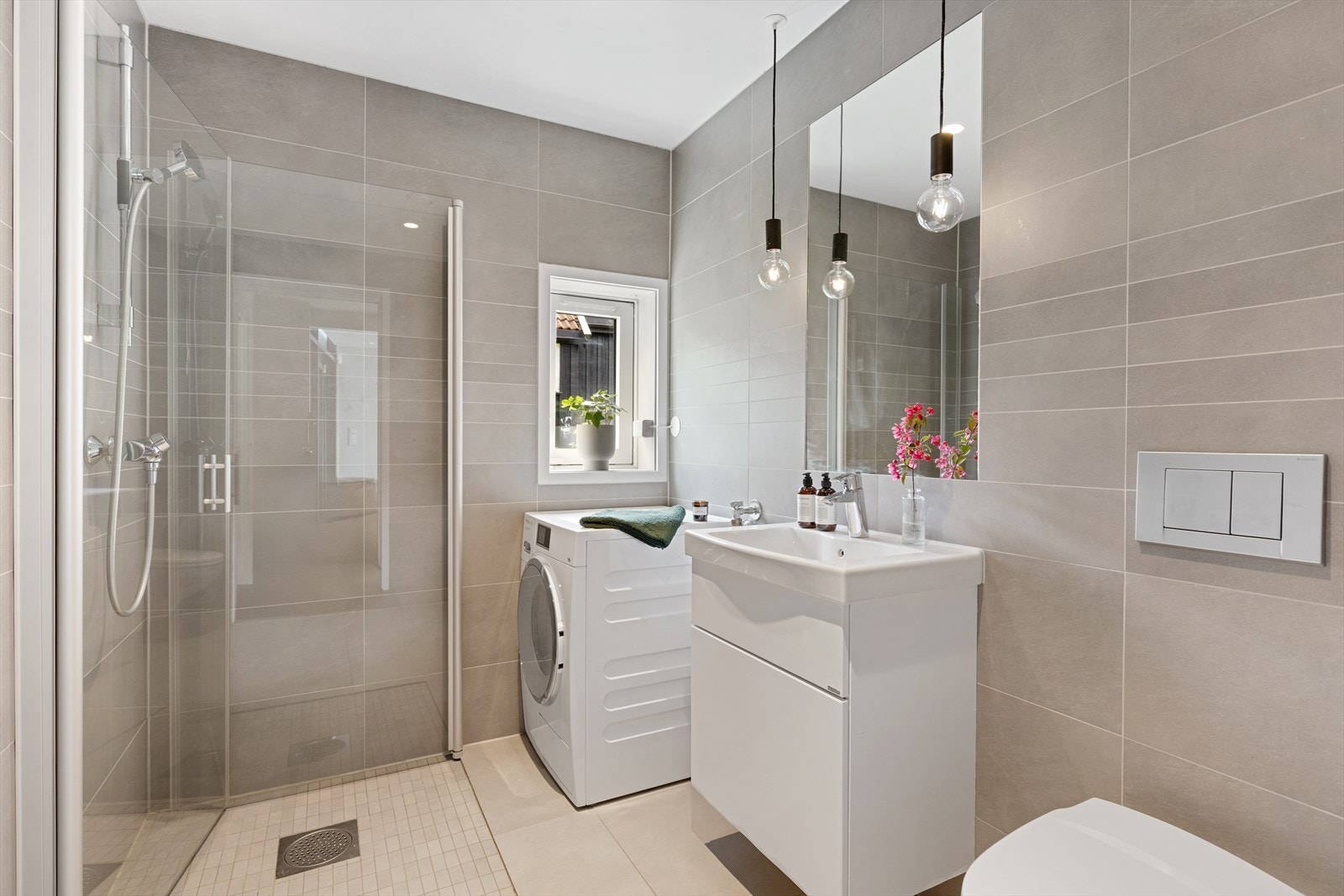 Pent, flislagt bad/vaskerom utstyrt med vegghengt toalett, innredning med servant, blandebatteri/dusjarmatur, dusjdører i glass samt opplegg for vaskemaskin. Galleribilde