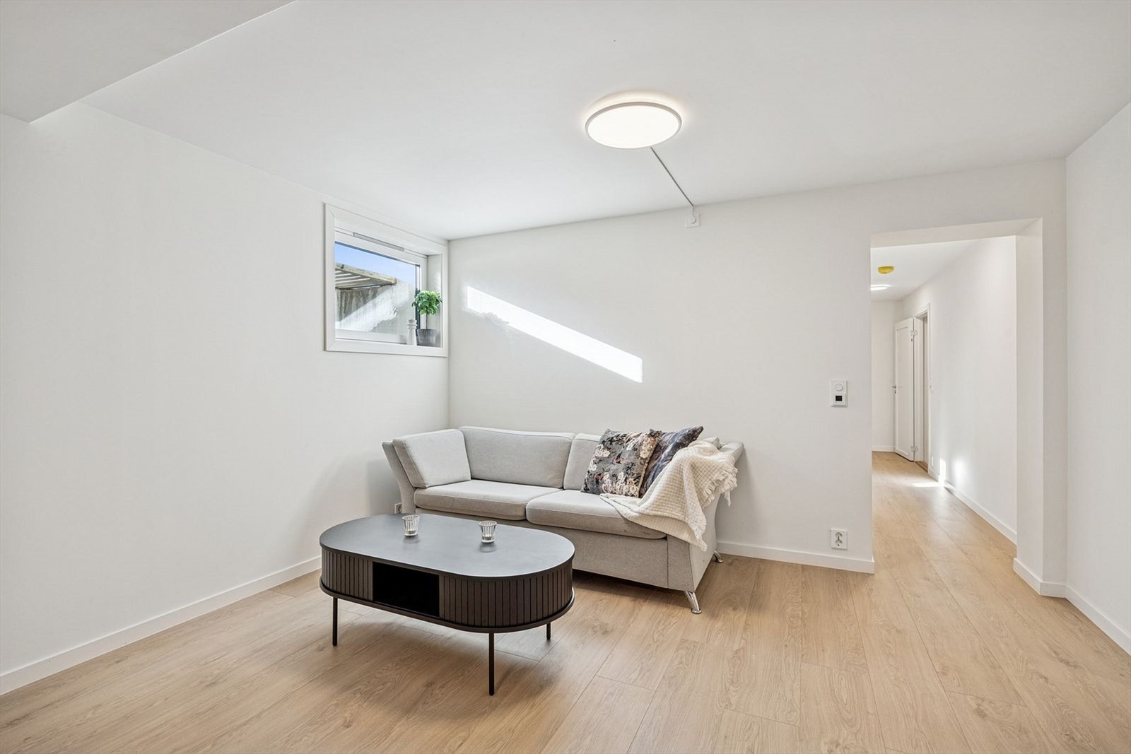 Det er plass til spisebord ved veggen, og rommet har lyse gulv og nøytrale farger som gir et rent og stilfullt uttrykk. Stuen er innredet med sofa og salongbord, og store vindusflater gir godt med naturlig lys. Galleribilde