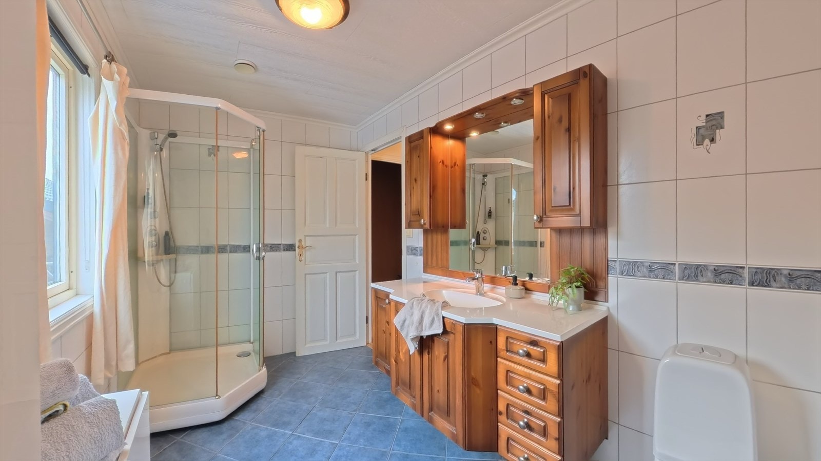 Helfliset bad innredet med vask med skapinnredning, dusjkabinett og toalett. Galleribilde