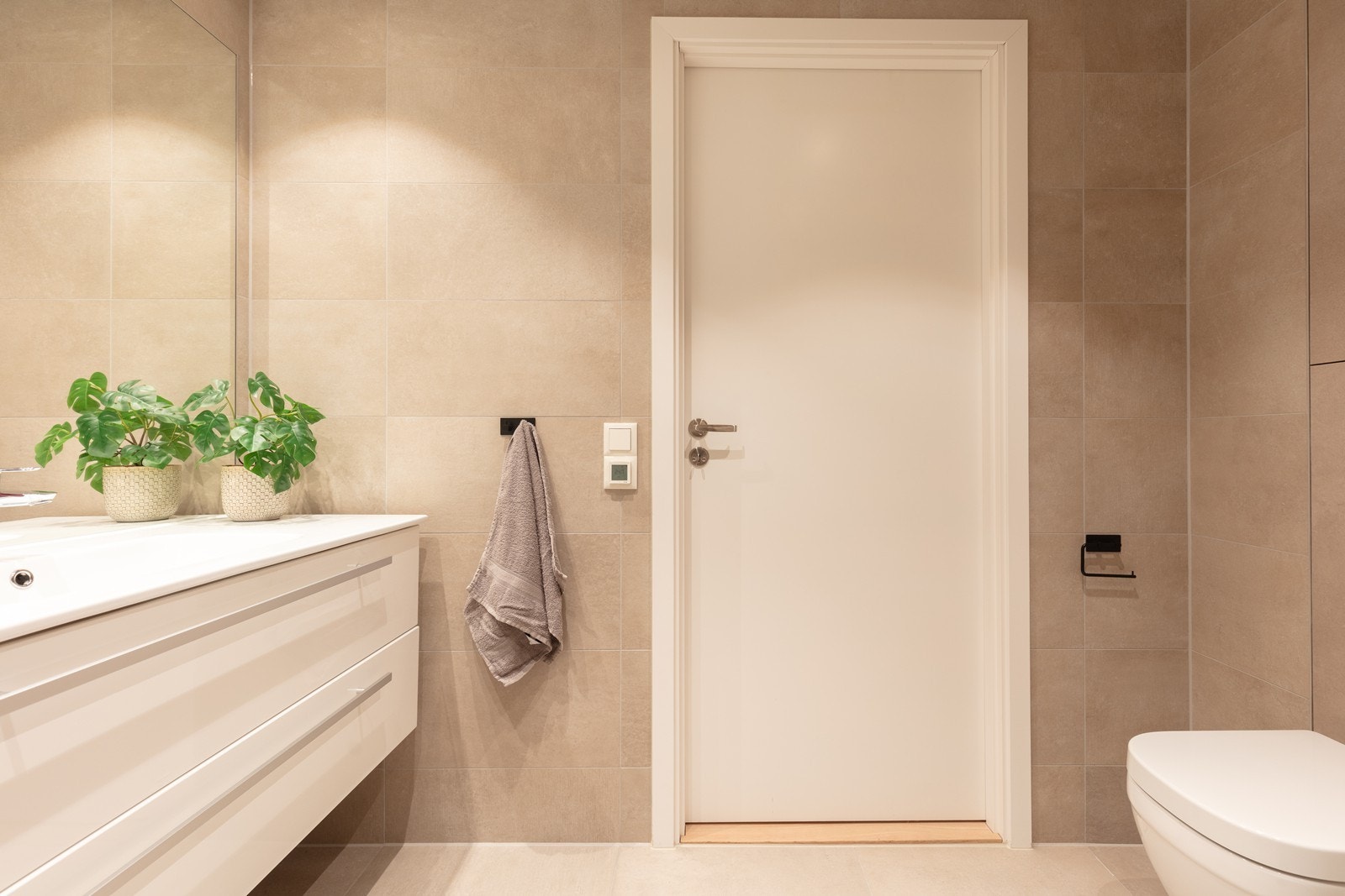 Badet har veggmontert toalett og store 30x60 cm fliser på veggene. Galleribilde