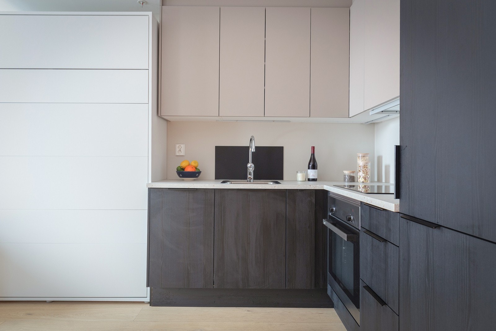 Stilrent HTH-kjøkken fra 2023 med integrerte hvitevarer og mørke fronter. Galleribilde