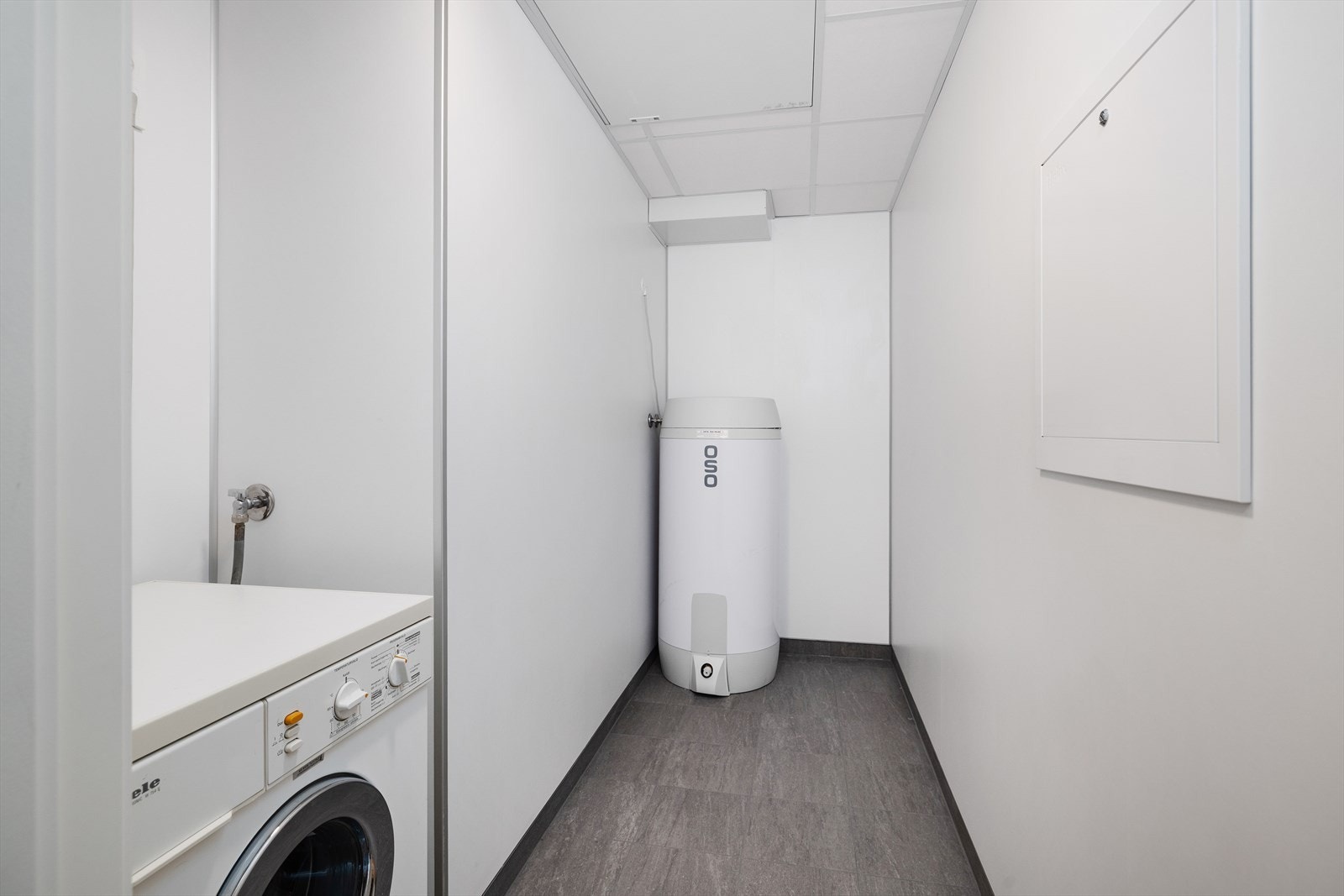 En praktisk innvendig bod med opplegg for vaskemaskin og plass til lagring. Galleribilde