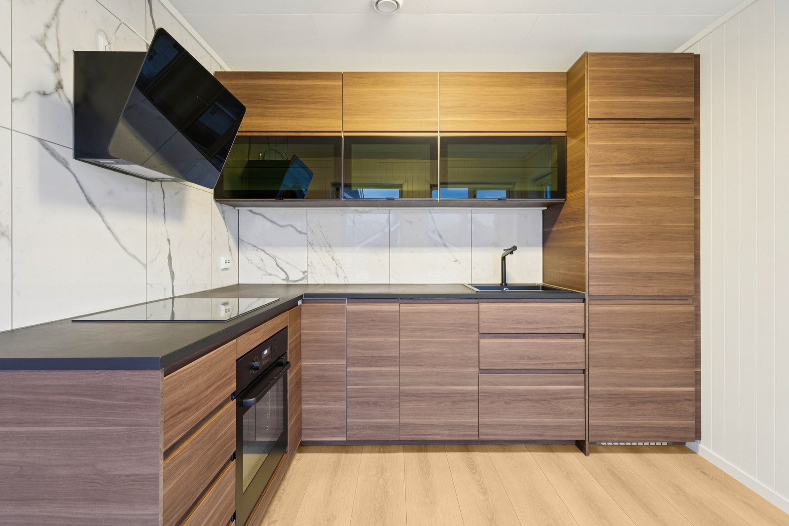 Nyinnstalert kjøkken med moderne, glatte fronter, laminert benkeplate og en stilren sort vask med matchende blandebatteri Galleribilde