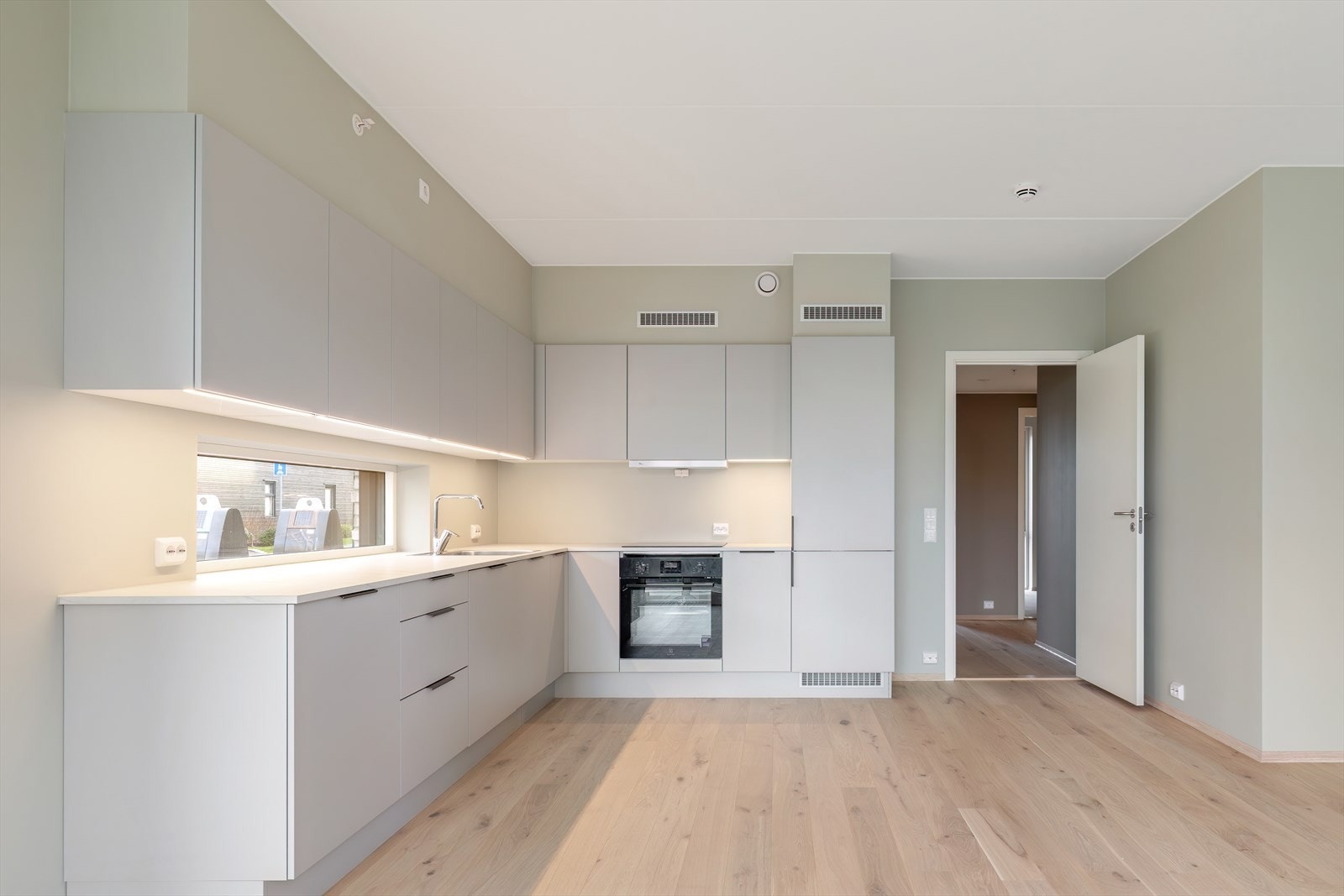 Kjøkkenet har en åpen planløsning med lys innredning og parkettgulv. Galleribilde