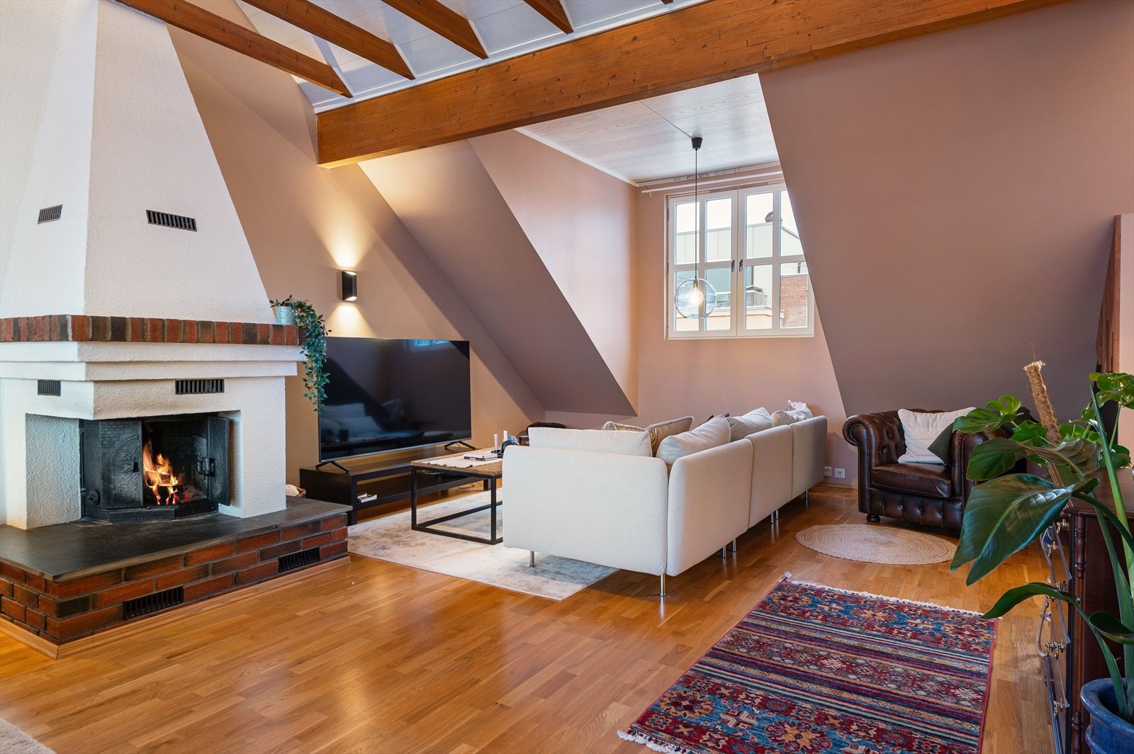 Peis med murstein gir varme og atmosfære til oppholdsrommet, synlige bjelker gir romslig takhøyde. Galleribilde