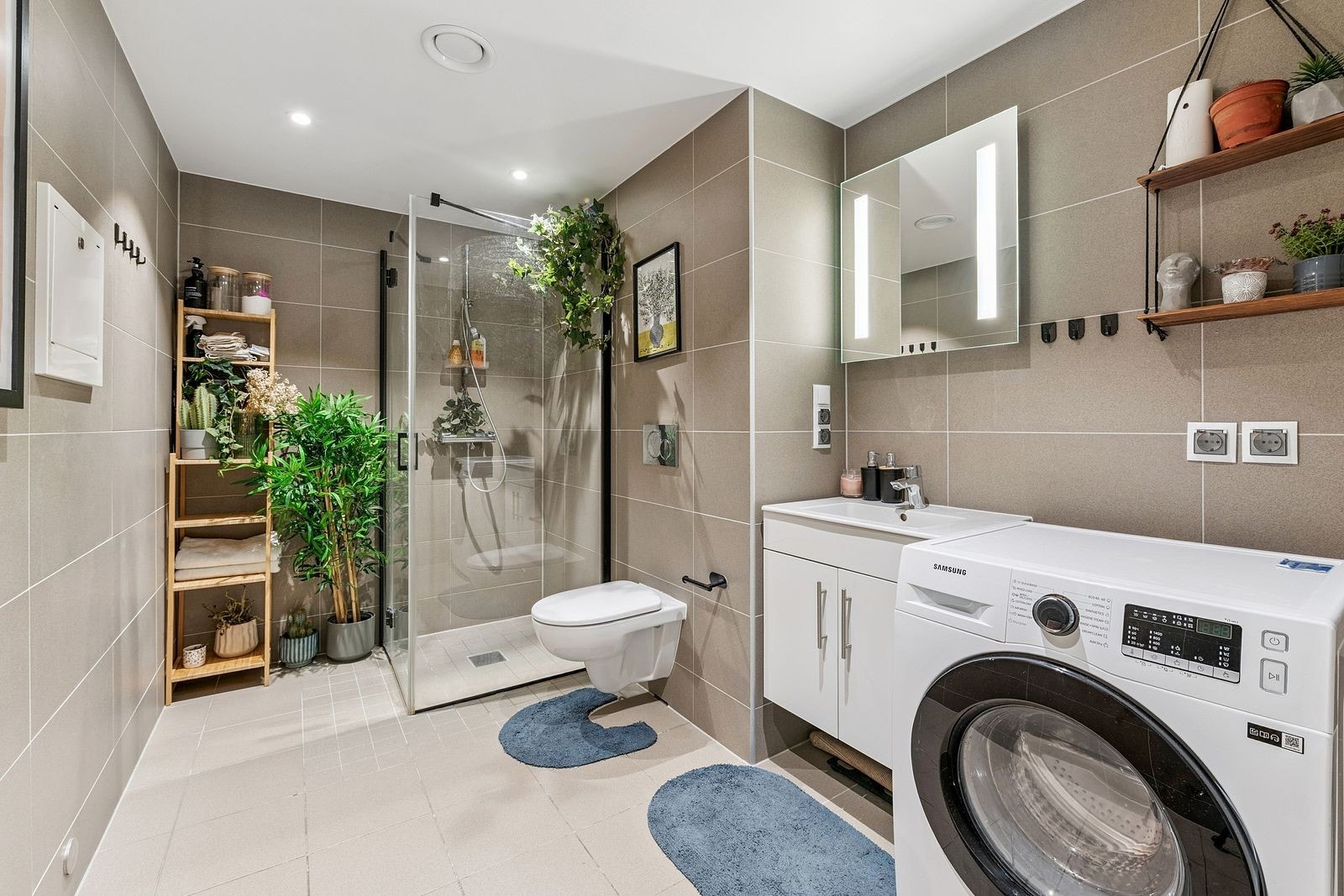 Delikat og flislagt bad som er av sjenerøs størrelse med Opplegg til vaskemaskin og tørketrommel Galleribilde