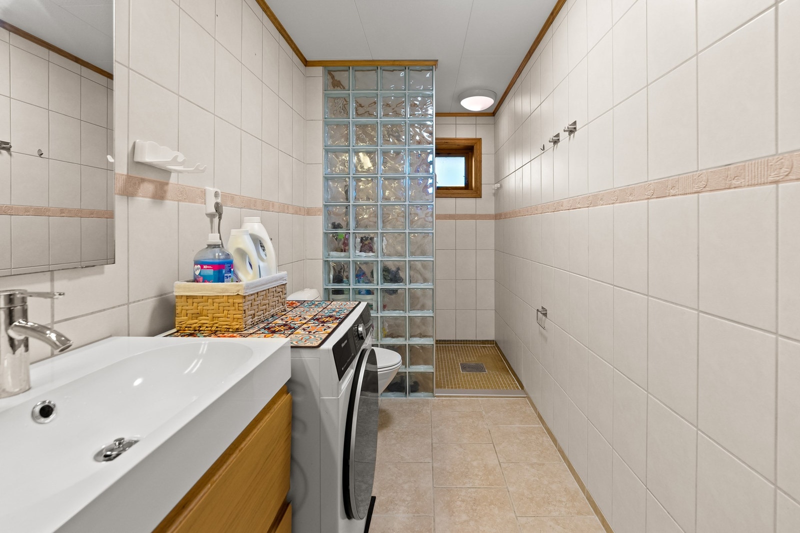 Badet i 1 etasje er fra byggeår. Det er flislagt gulv med elektrisk gulvvarme og flislagte vegger. Galleribilde