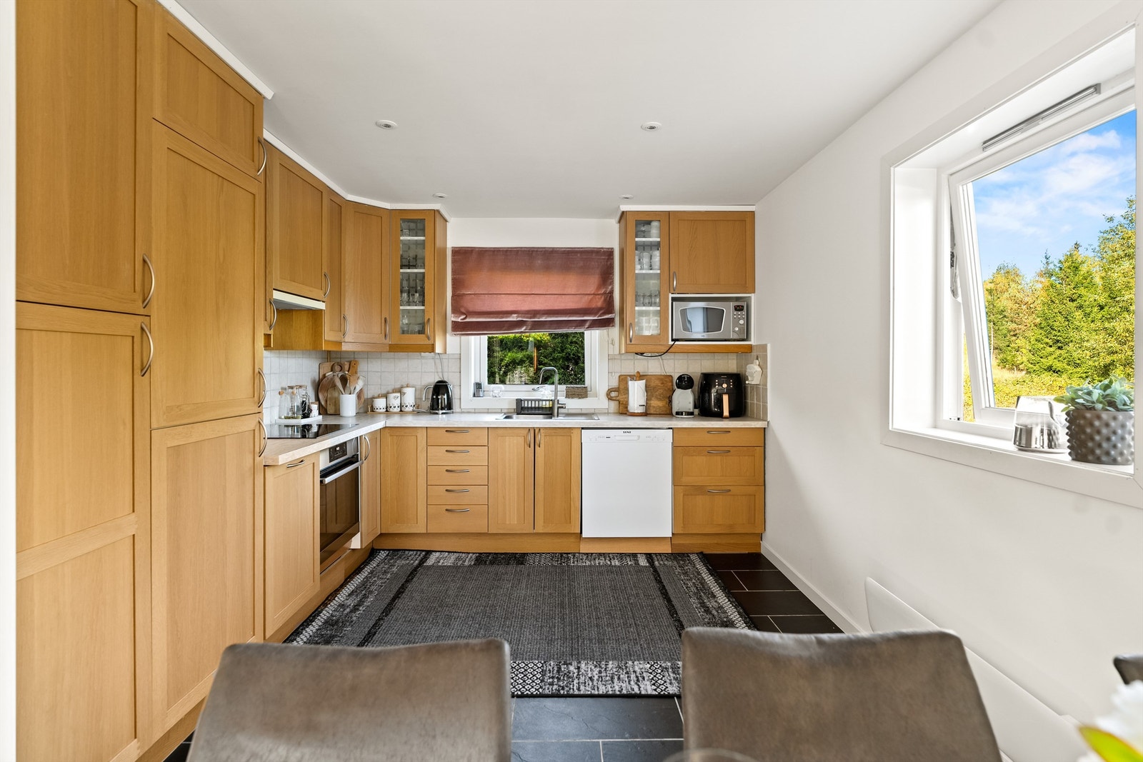 Det er stor åpen kjøkkenløsning fra byggeår. Kjøkkeninnredningen er med slette fronter og laminert benkeplate. Galleribilde