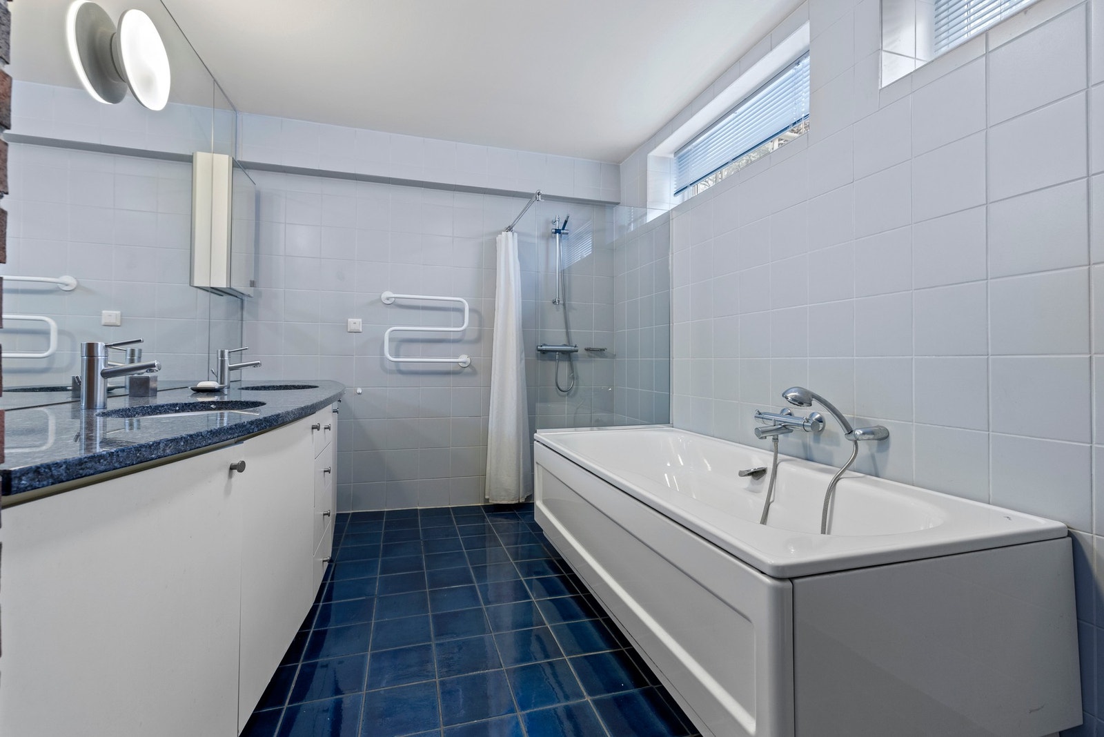 Romslig, flislagt bad med gulvvarme som har både badekar og dusjhjørne. Galleribilde