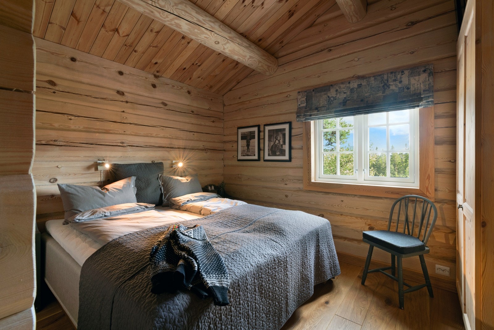 Soverom med tømmervegger, stor seng, vindu som gir naturlig lys og utsikt mot naturen. Galleribilde