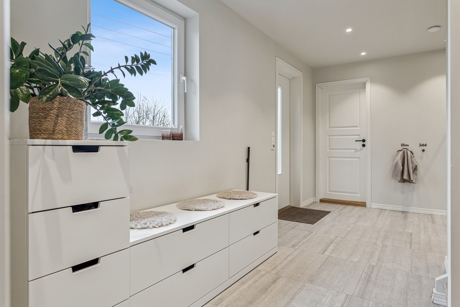 Lys og lekker gang med flislagt gulv som tåler aktiv bruk, malte vegger og malt himling. Varme i gulv. Galleribilde