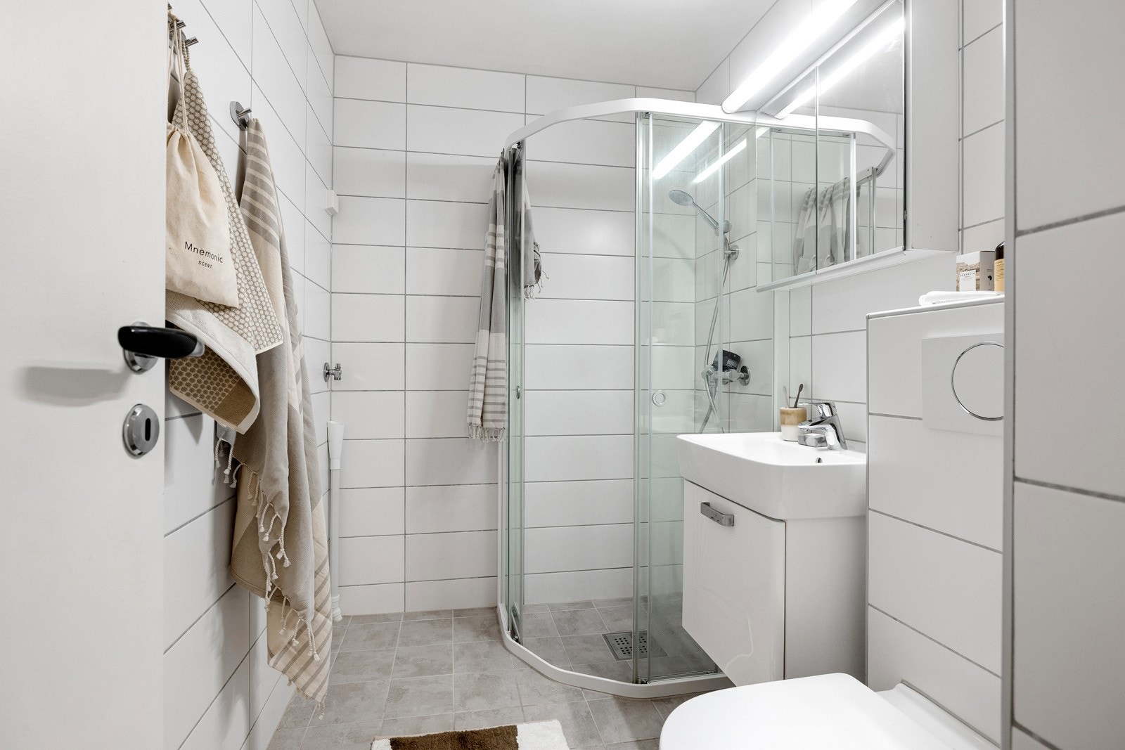 Badet er utstyrt med gulvvarme, mekanisk avtrekk, servant med underskap, speilskap med belysning, toalett, dusjhjørne med skyvedører i glass, samt opplegg for vaskemaskin. Galleribilde