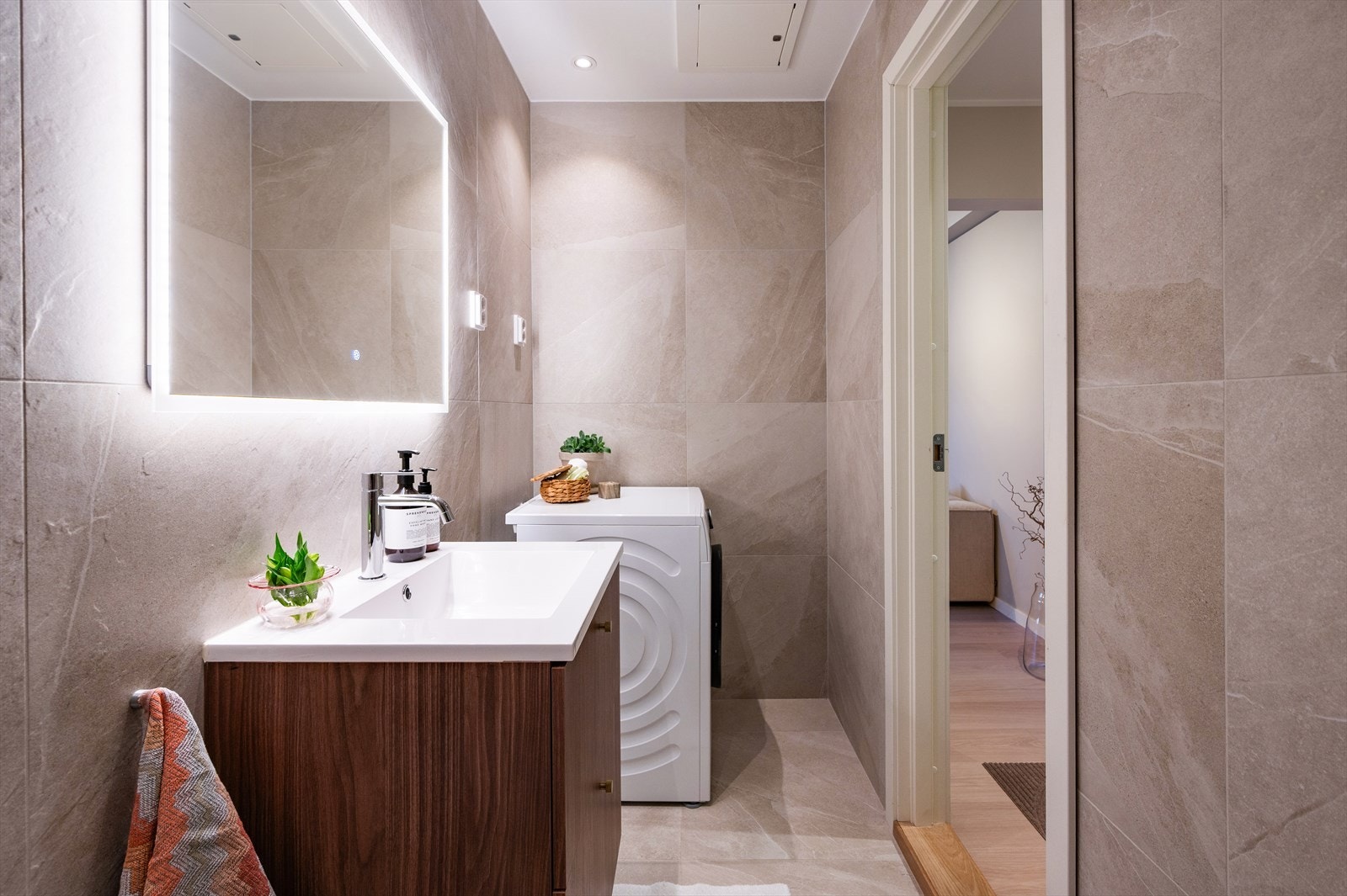 Opplegg for vaskemaskin. Naturlig ventilasjon. Himling med malte plater og innfelte downlights. Vegger og gulv er belagt med fliser, og det er elektrisk gulvvarme. Galleribilde