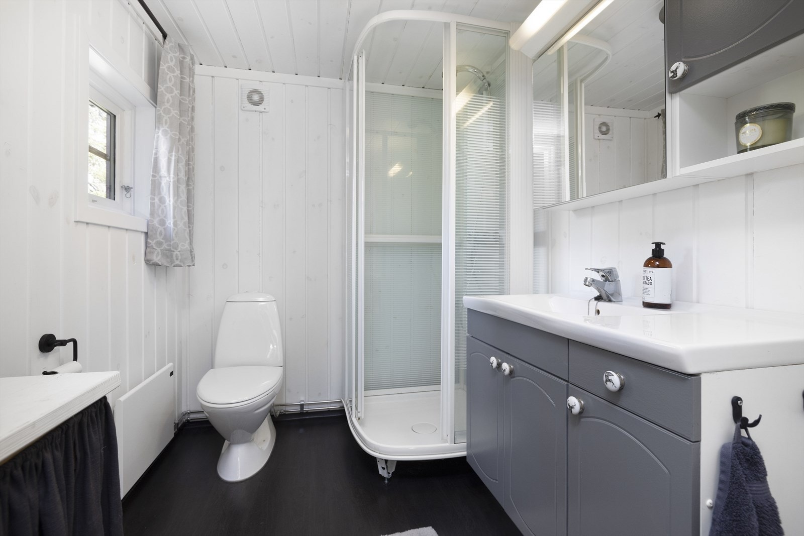 Badet har innredning med servant topp. Det er montert toalett og dusjkabinett. Galleribilde