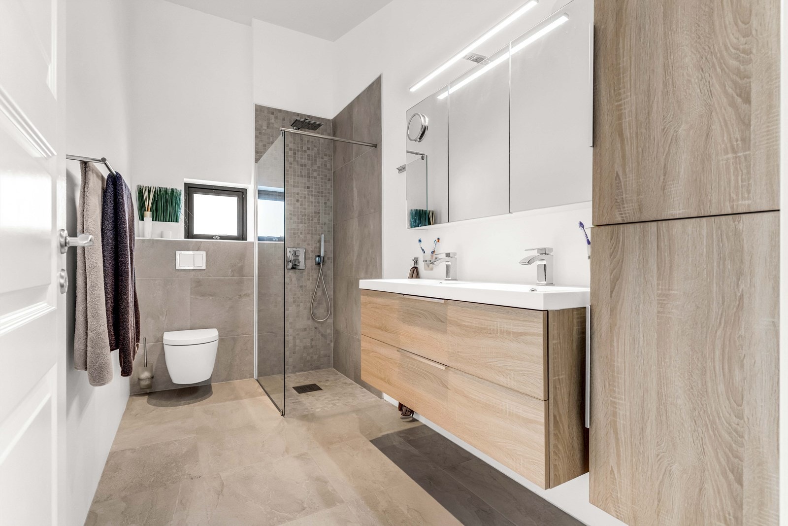 Etasjen har et flislagt baderom med vannbåren gulvvarme. Innredningen består av servantskap med nedfelt dobbel servant med underskuffer og 1-greps blandebatteri, dusjhjørne med glassvegg og vegghengt toalett. Galleribilde