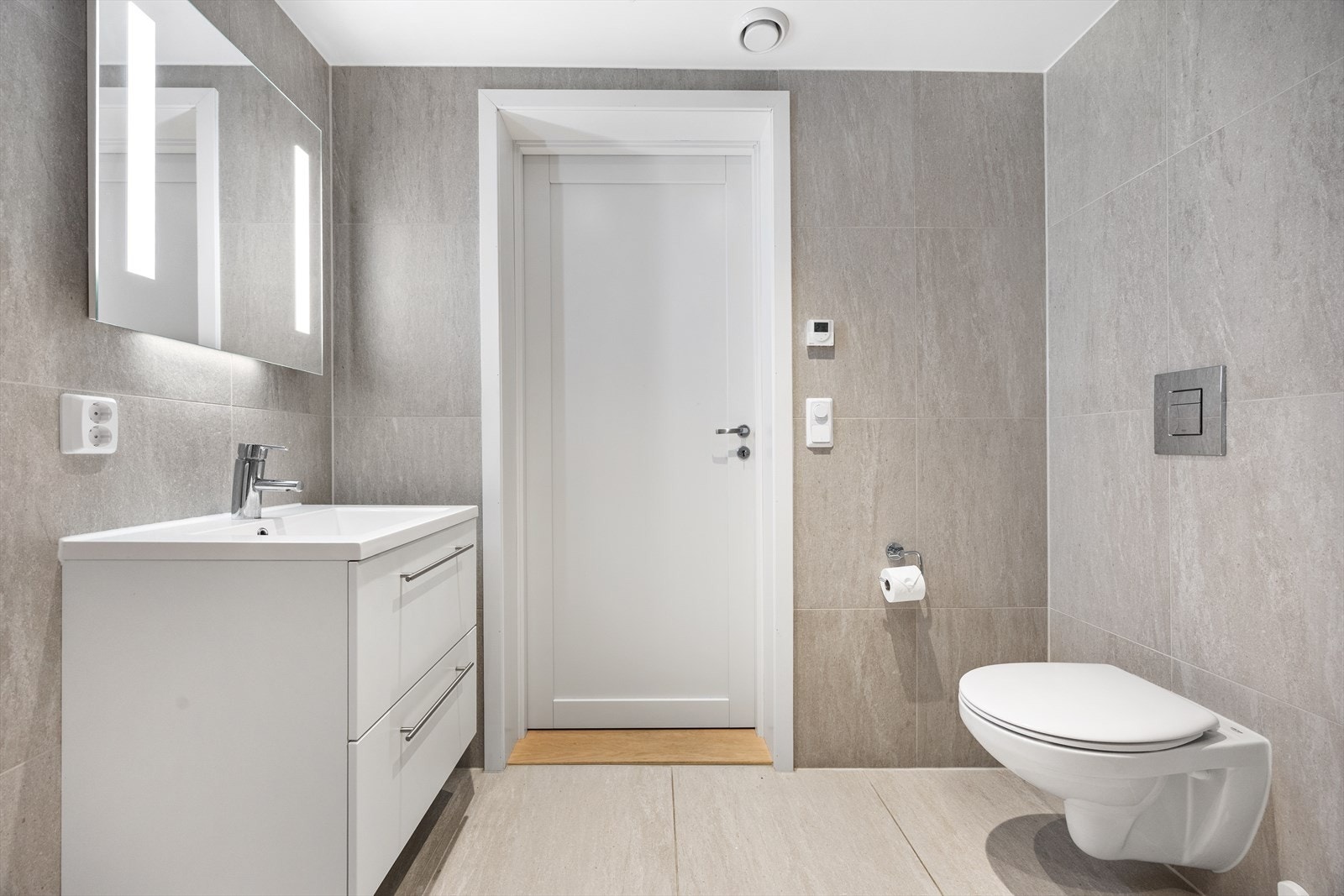 Innredning bestående av servant med underskap, speil med belysning, vegghengt toalett og dusjsone. Galleribilde