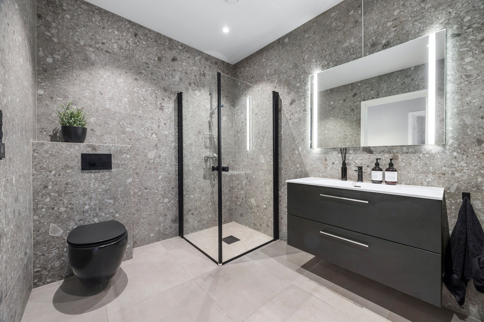 Badet har en delikat innredning med slette fronter og nedfelt servant med ettgreps blandebatteri Galleribilde